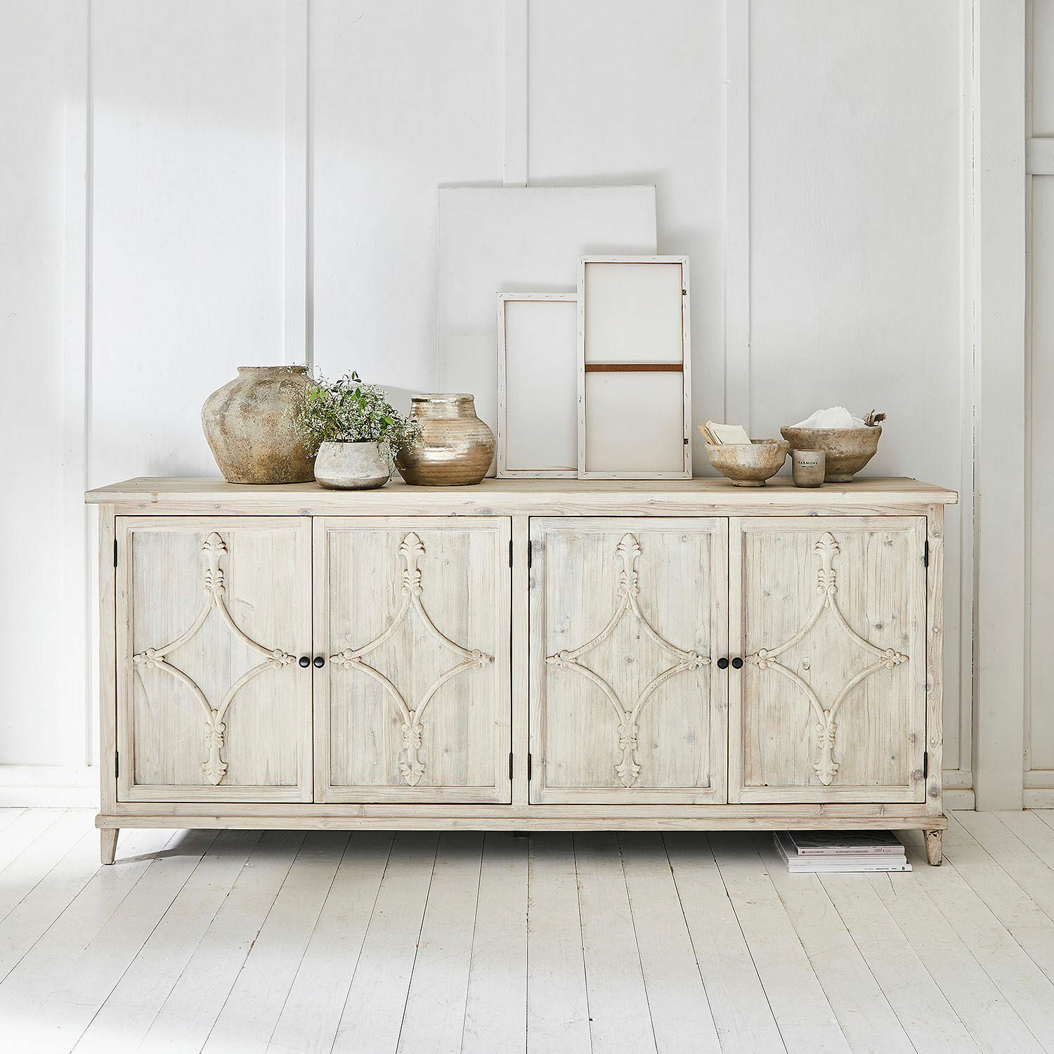 Commode Pemberton Buffet en bois clair avec portes décoratives et objets en céramique posés dessus dans un intérieur lumineux