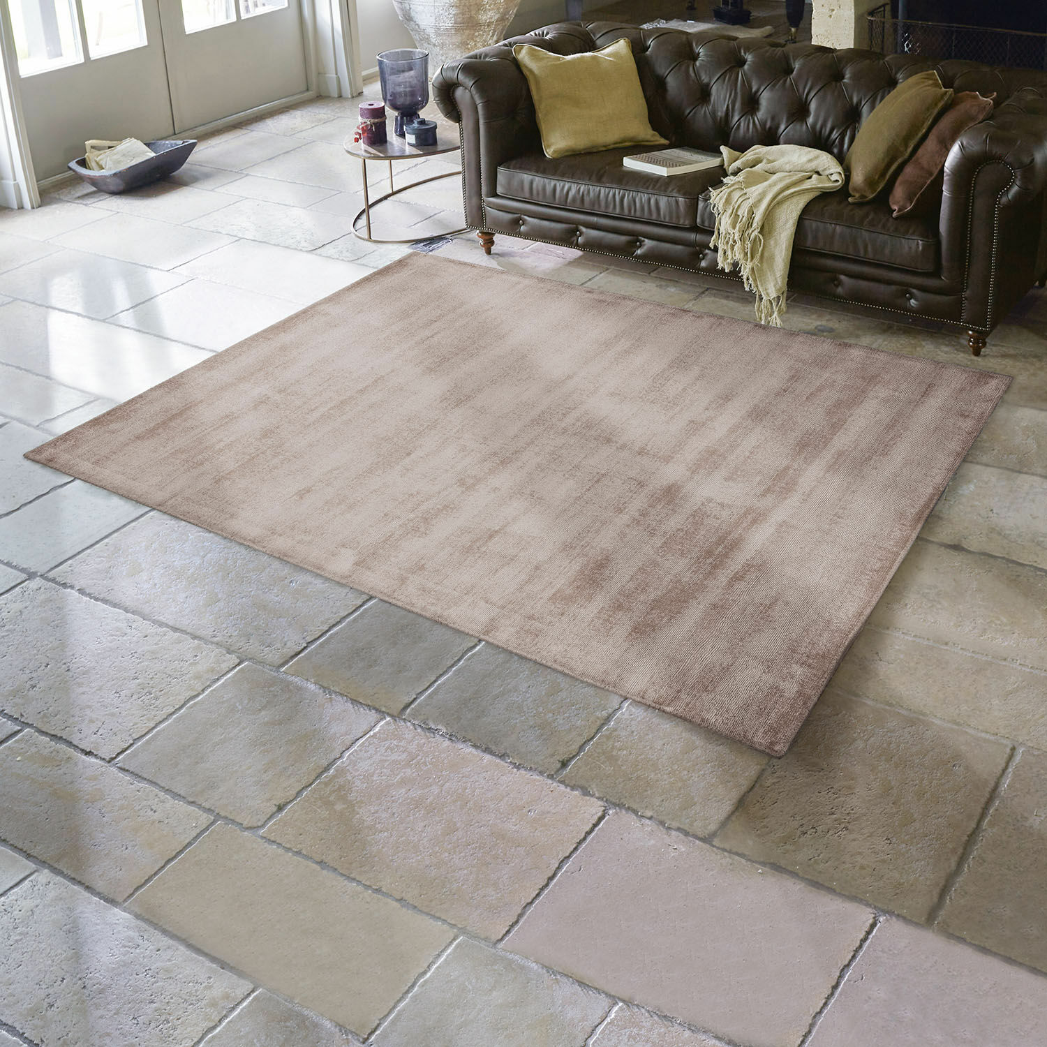 Tapis Mariselle Tapis beige en tissu doux sur sol en pierre dans un salon avec canapé en cuir marron