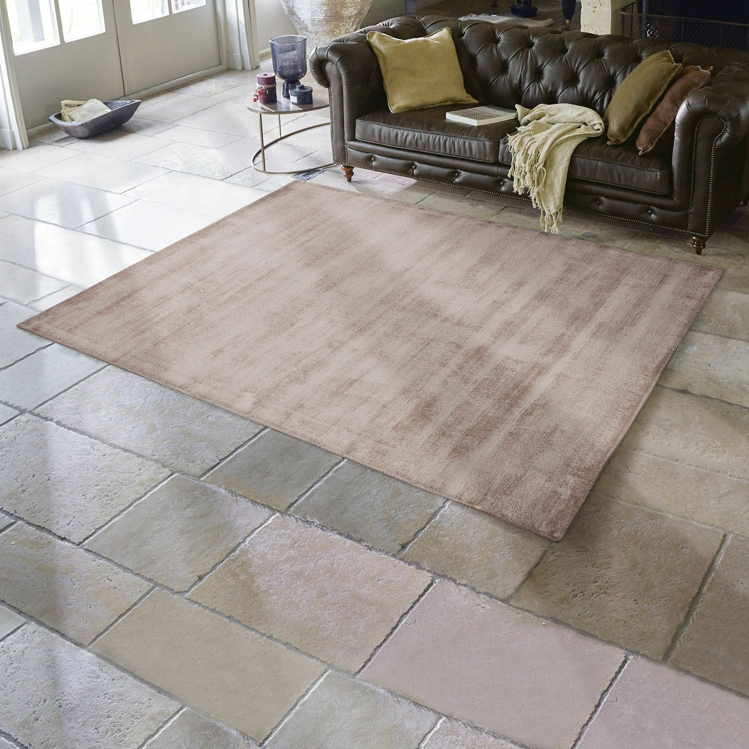 Tapis Mariselle Tapis beige en tissu doux sur sol en pierre dans un salon avec canapé en cuir marron