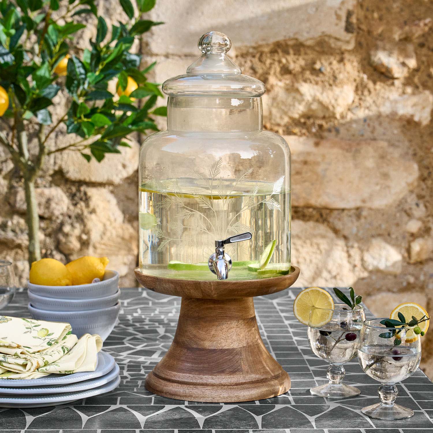 Distributeur de boissons en verre avec couvercle sur socle en bois rempli d'eau citronnée
