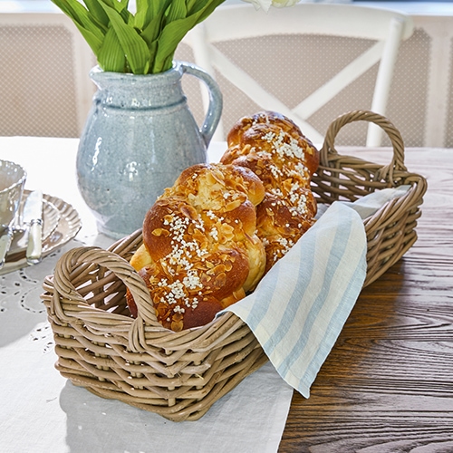 Panier en osier avec poignées et torchon en lin sur table en bois dans une salle à manger