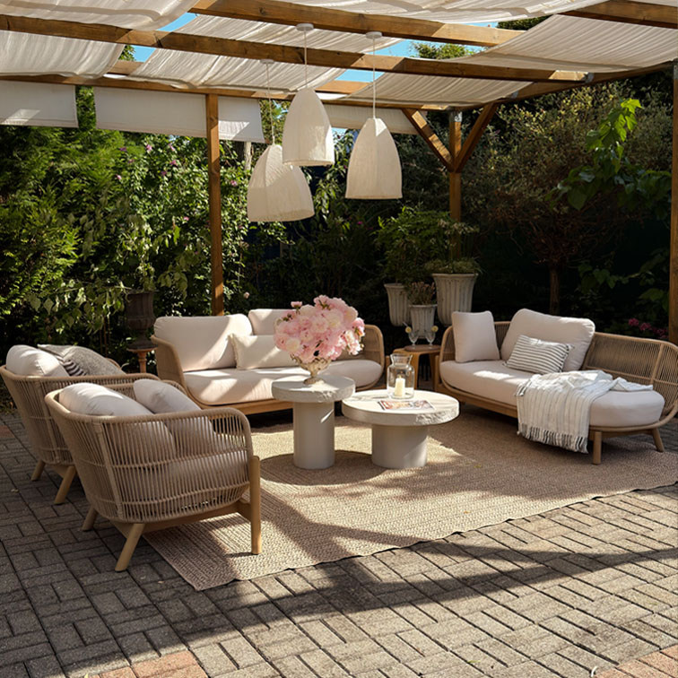 Ensemble de mobilier de jardin beige avec coussins et structure en bois sous une pergola avec suspensions blanches
