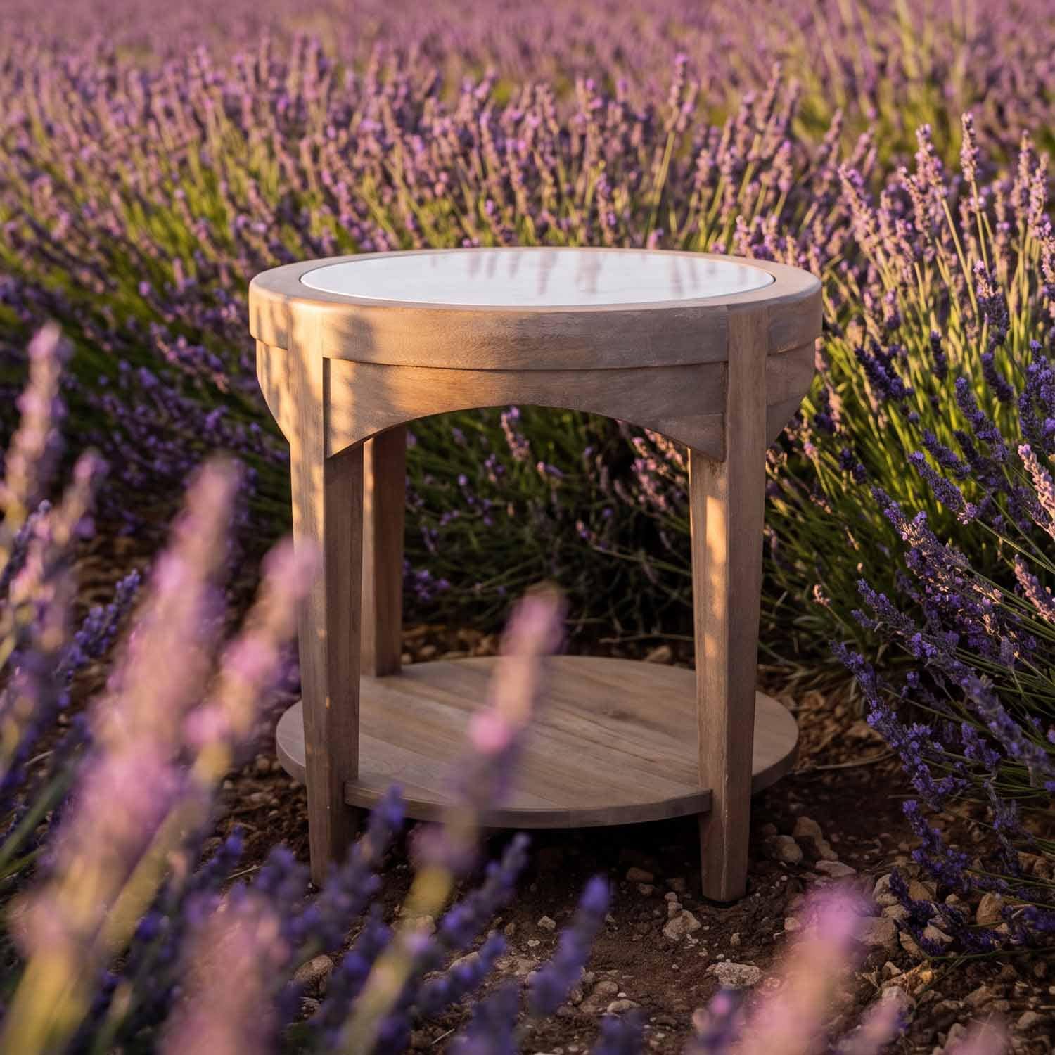Table ronde en bois avec plateau blanc, placée au milieu de fleurs de lavande violettes en extérieur