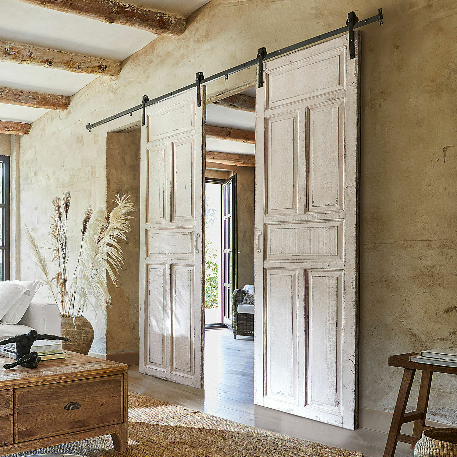 Double porte coulissante Mallothra Portes coulissantes blanches en bois avec système métallique dans un intérieur rustique avec décorations naturelles