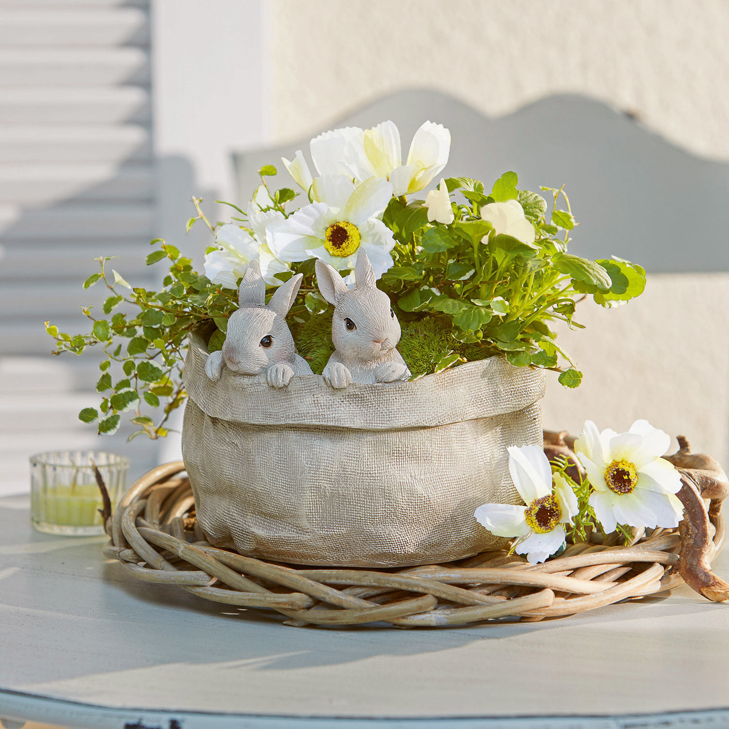 Cache-pot Mouriel Pot décoratif en tissu beige avec fleurs blanches et figurines de lapins sur un support en osier