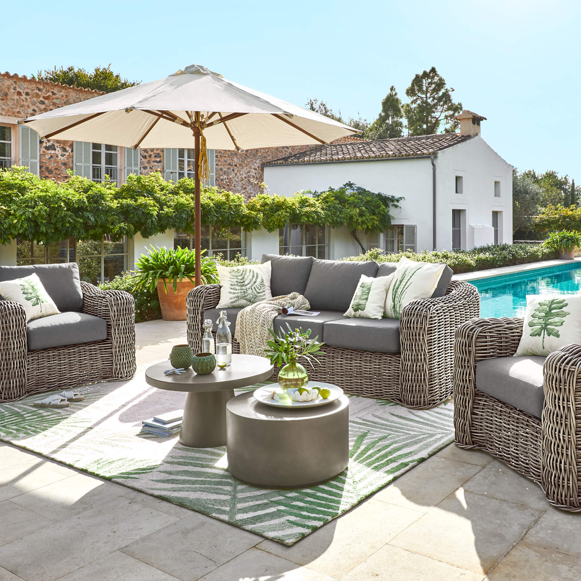 Ensemble de mobilier de jardin en technorattan gris avec coussins et parasol près de la piscine