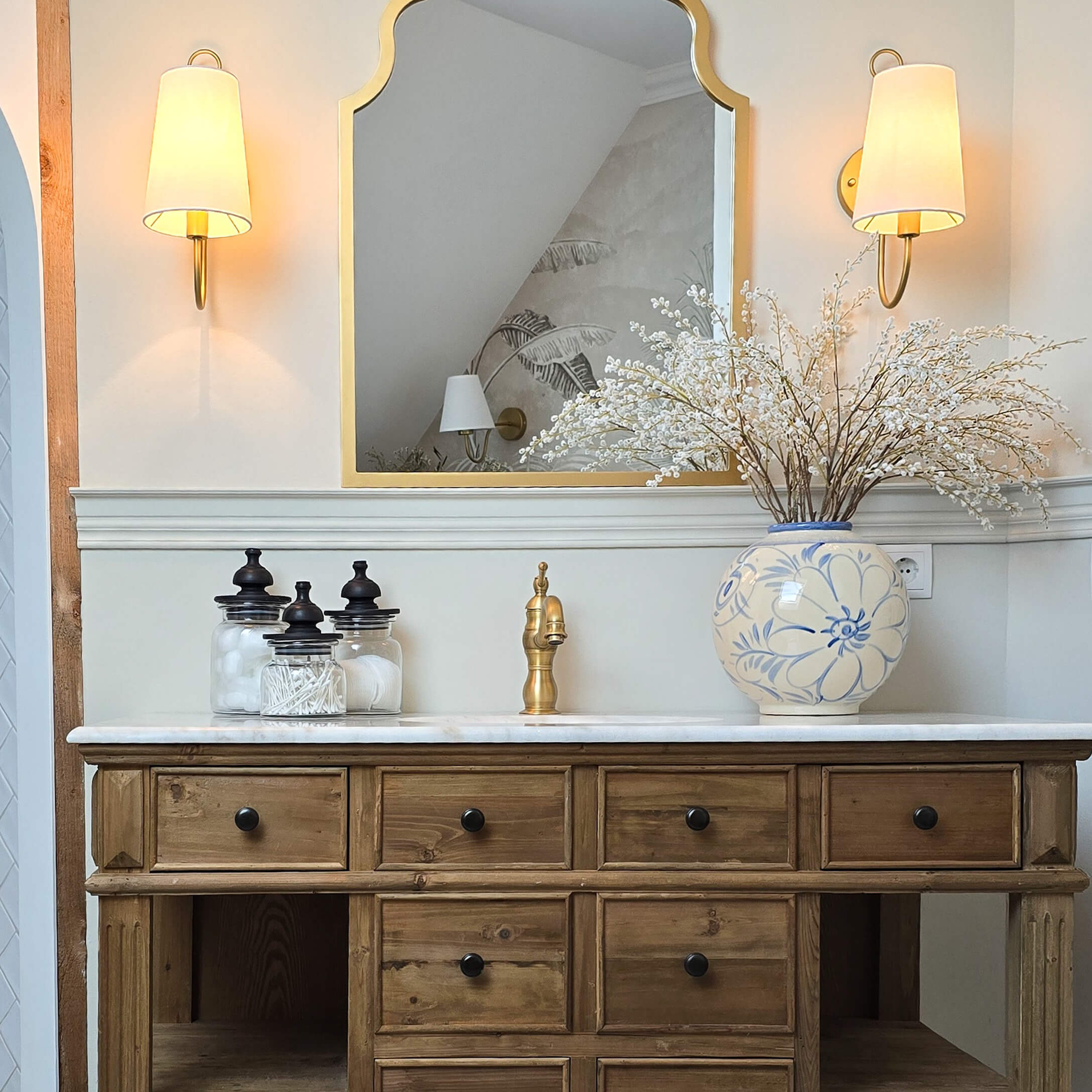 Commode en bois avec plateau en marbre, robinet doré et vase en céramique bleu et blanc avec fleurs