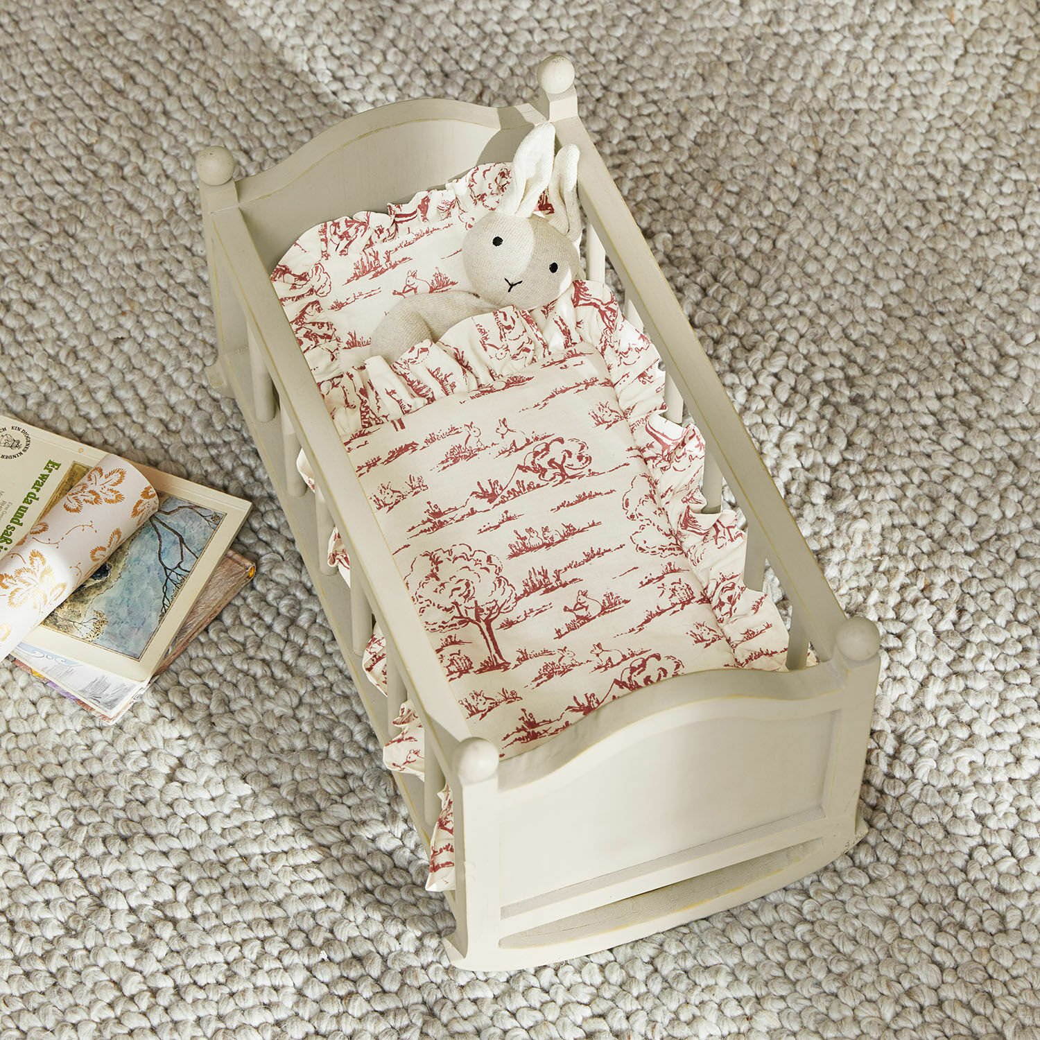 Berceau de poupée Erilea Petit lit en bois peint crème avec literie à motifs rouges et peluche lapin sur tapis gris épais