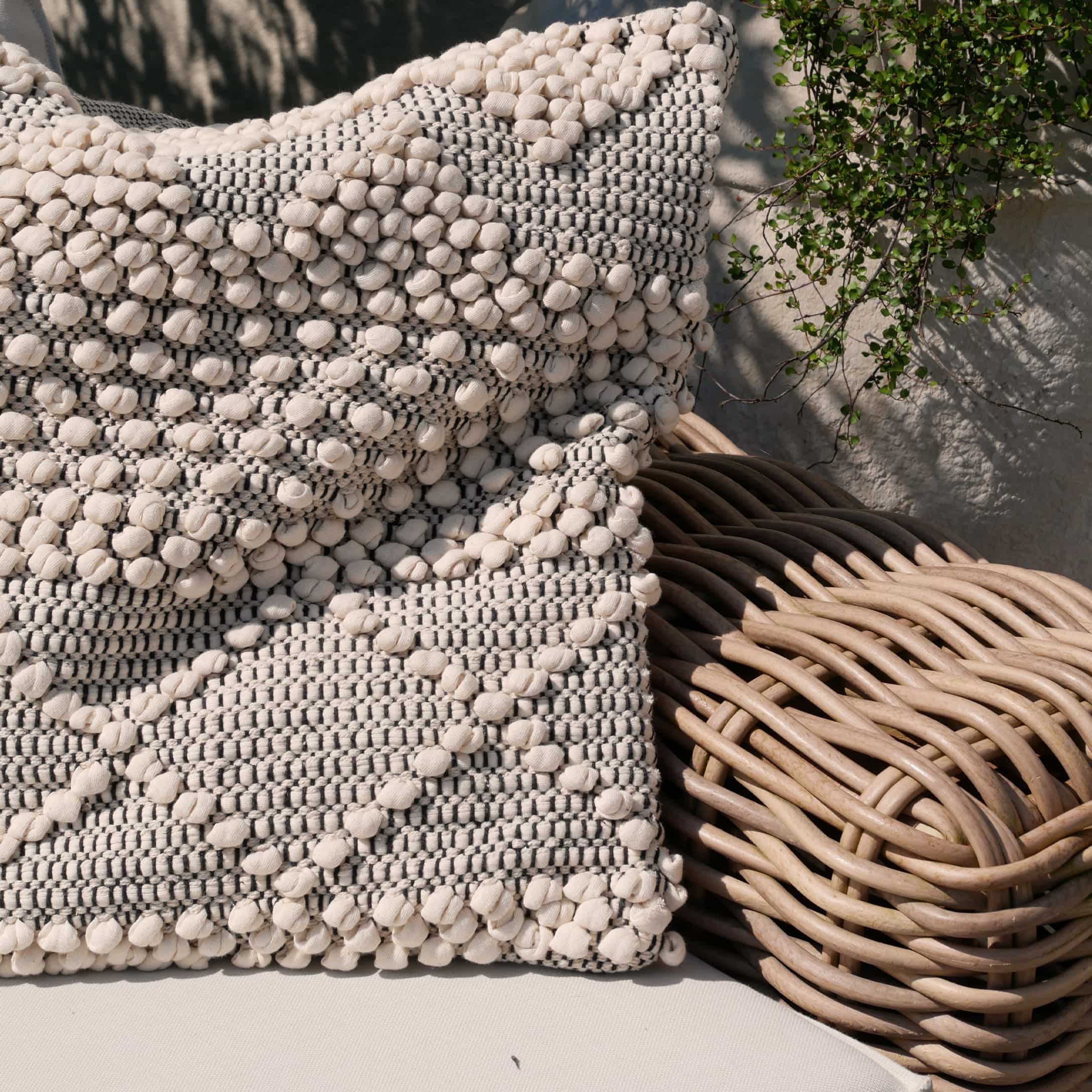 Coussin décoratif en coton beige et gris sur fauteuil en osier, style bohème moderne