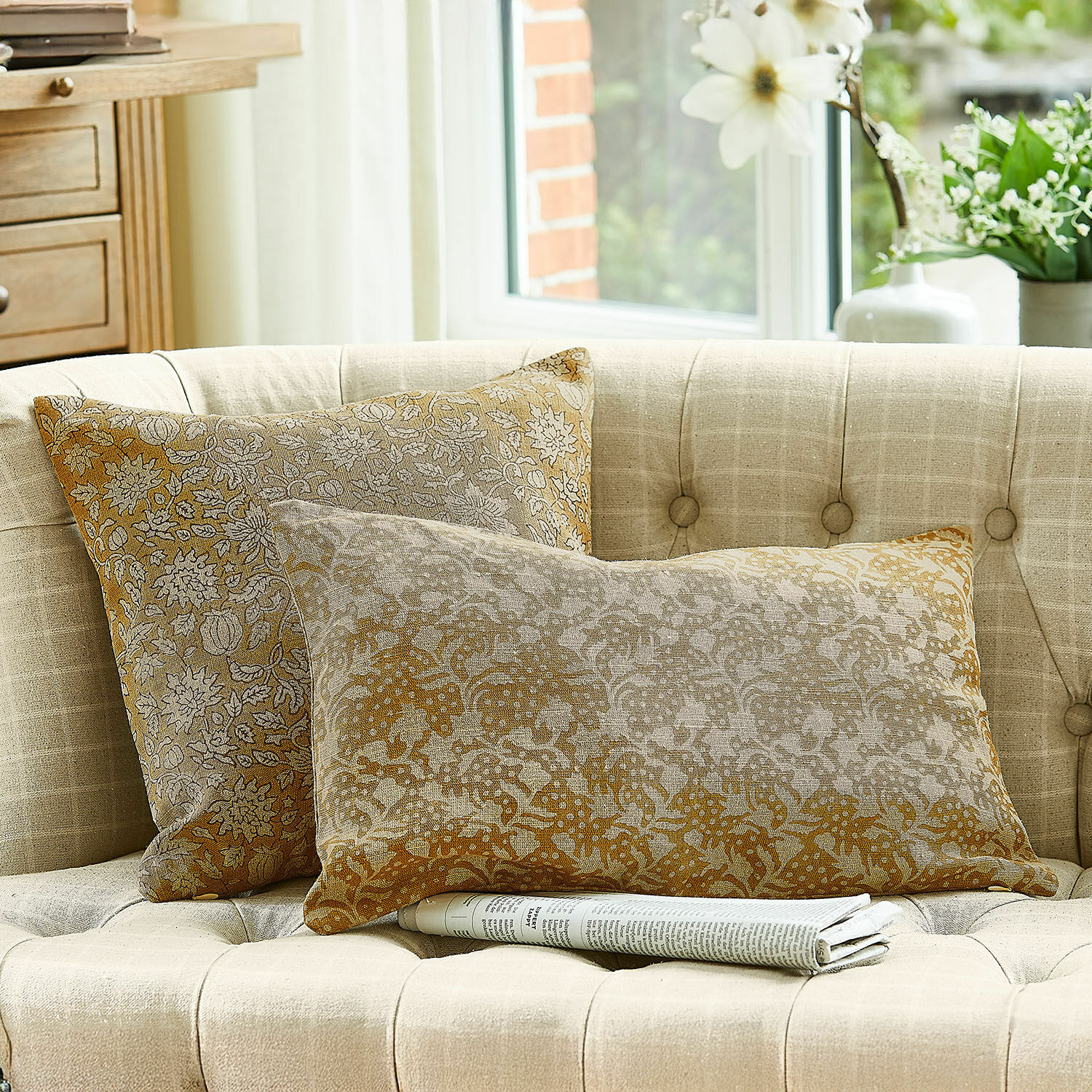 Lot de 2 housses de coussins Nalefor Deux coussins décoratifs en coton beige et marron sur un canapé clair dans un salon lumineux