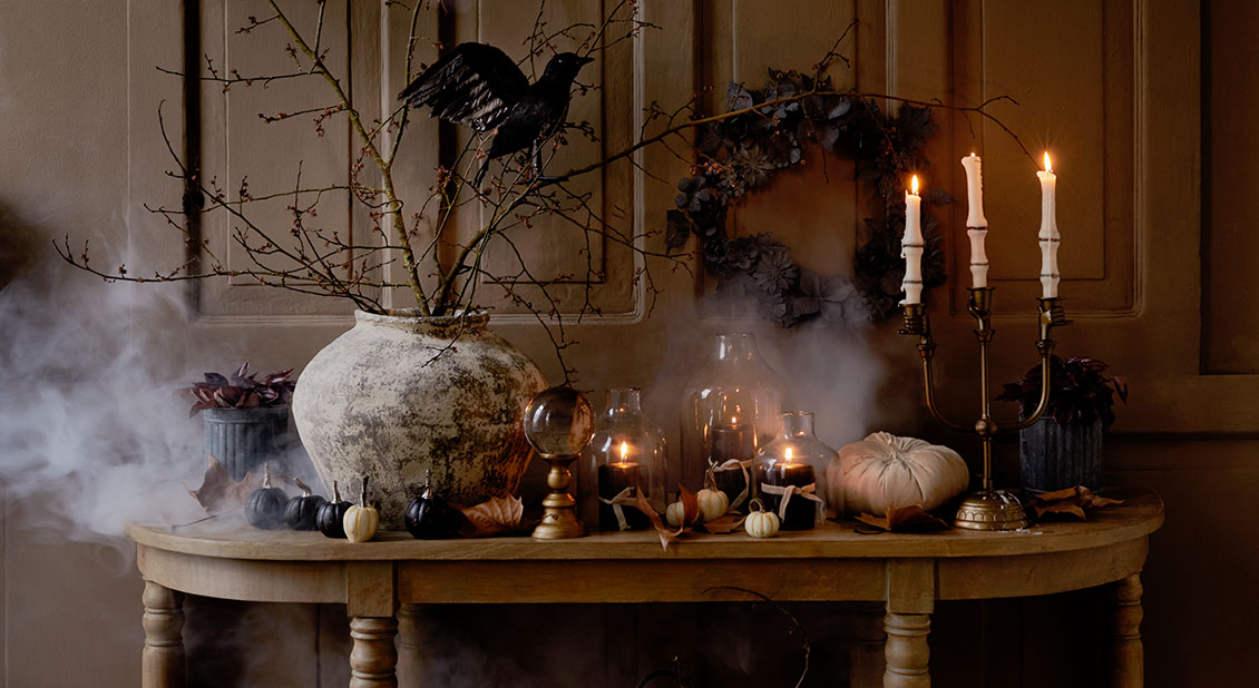 Table rustique décorée de citrouilles, bougies allumées et branches pour une ambiance automnale