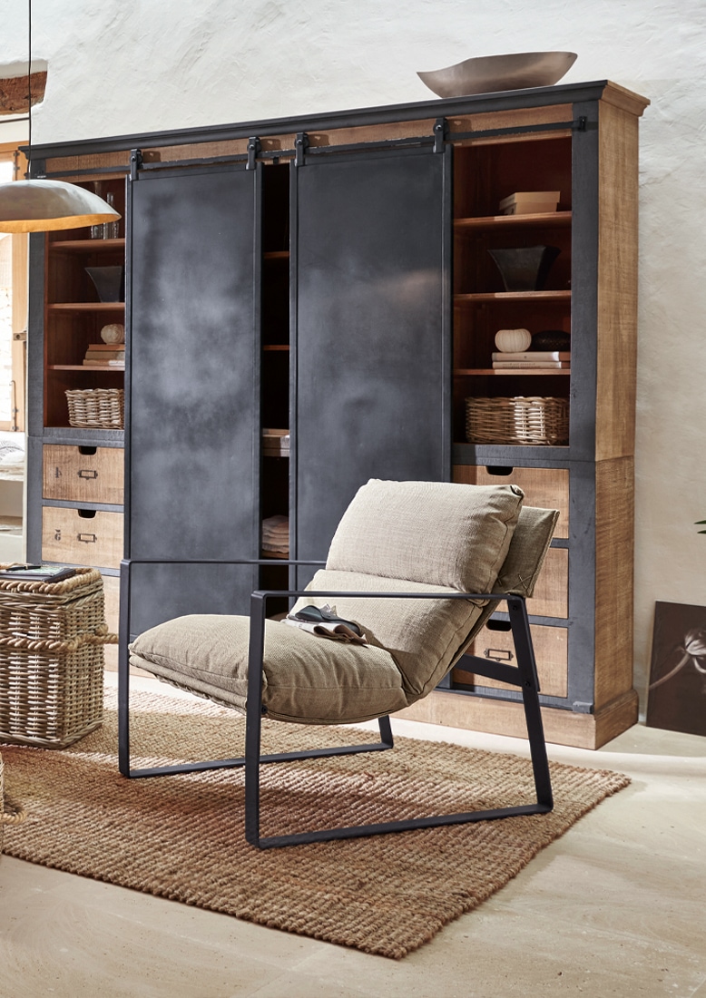 Fauteuil en tissu beige avec cadre en métal noir devant une armoire en bois avec portes coulissantes noires