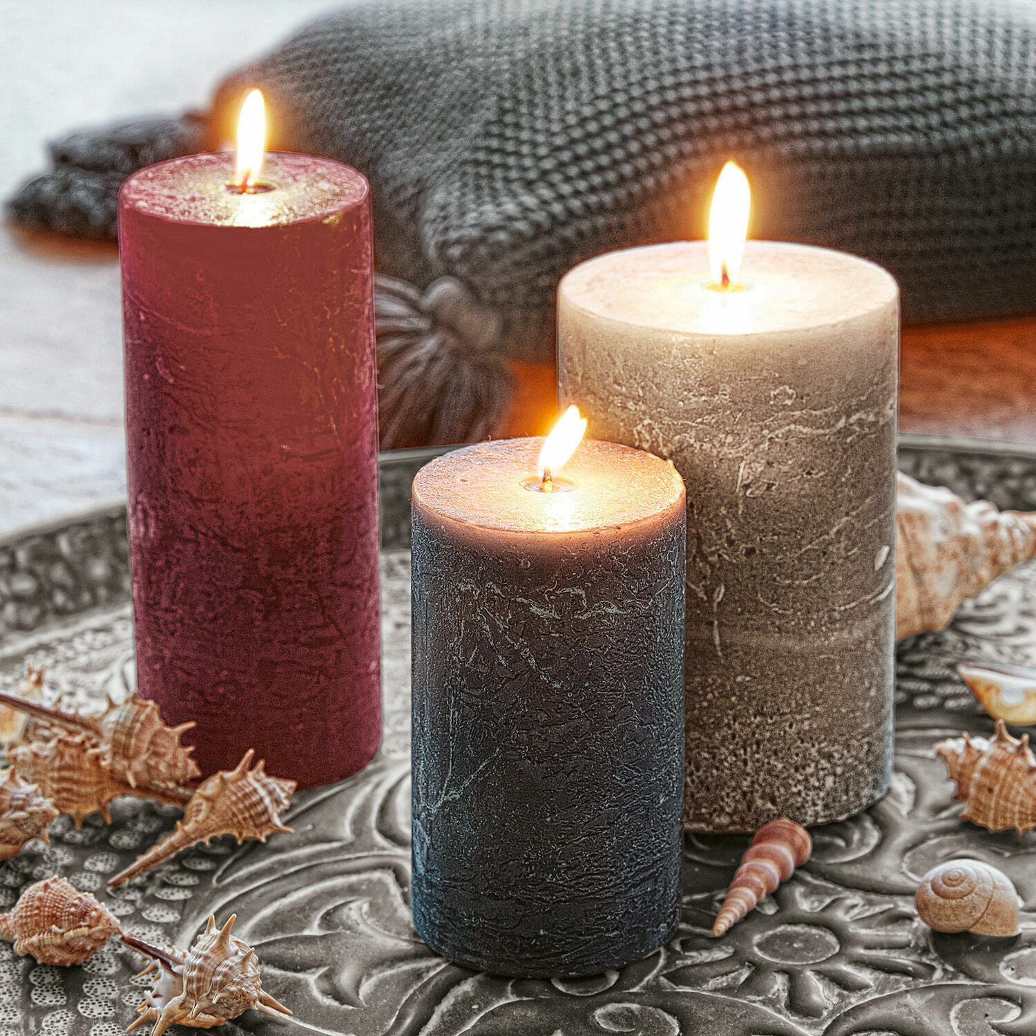 Lot de 3 bougies Pretin Trois bougies décoratives rouge, grise et noire sur un plateau en métal avec des coquillages