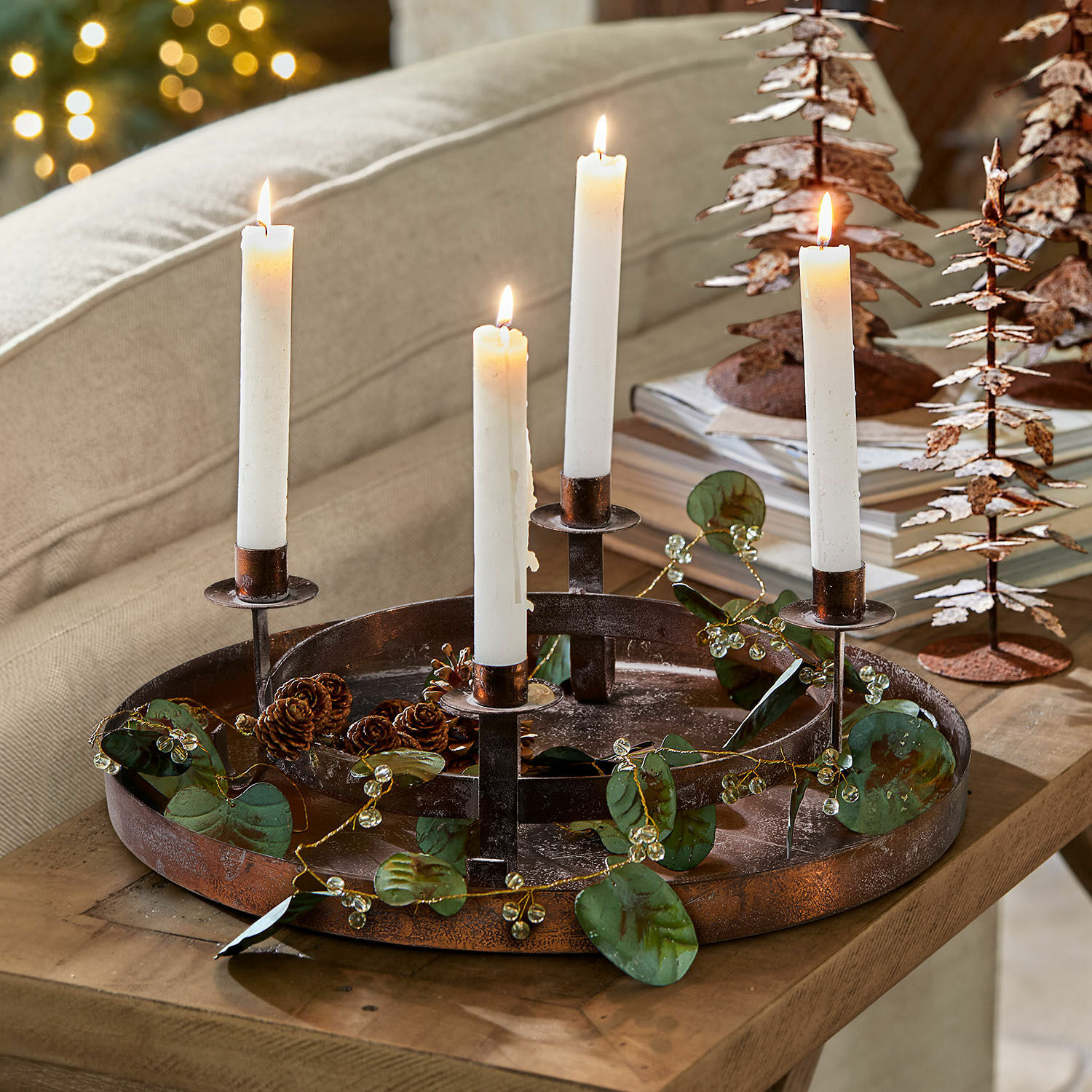 Couronne à bougies avec plateau Ivremont Chandelier en métal avec quatre bougies blanches et décoration de feuilles sur une table en bois