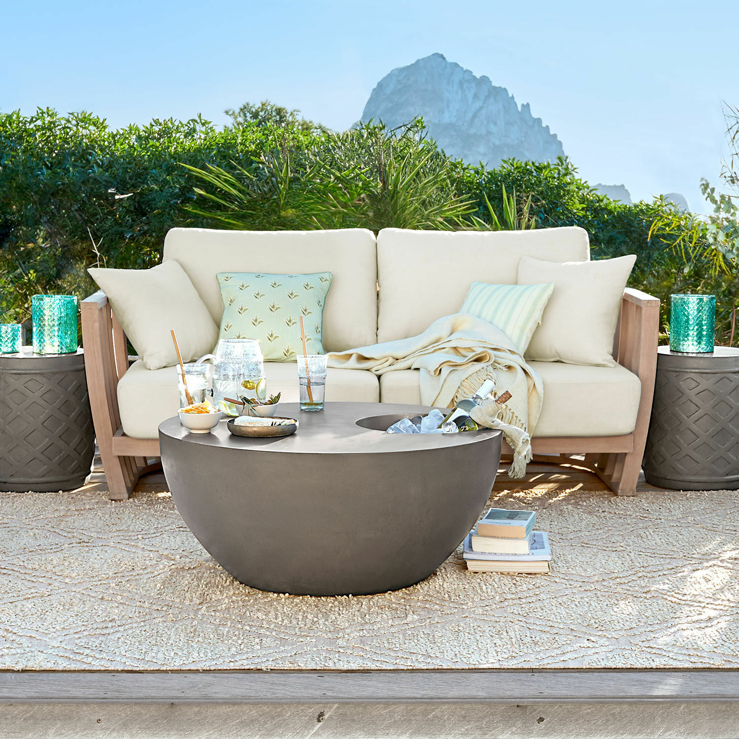 Canapé FSC®-100% Vézère Table basse ronde en béton gris moderne sur terrasse avec canapé beige et coussins décoratifs