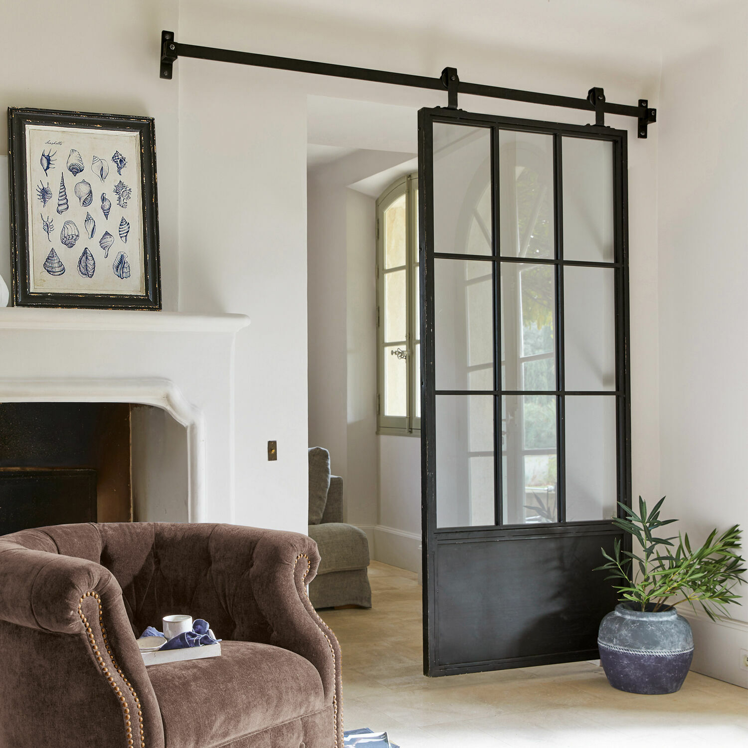 Porte coulissante Luisant Porte coulissante loft en métal noir et verre dans un intérieur moderne avec fauteuil et cheminée