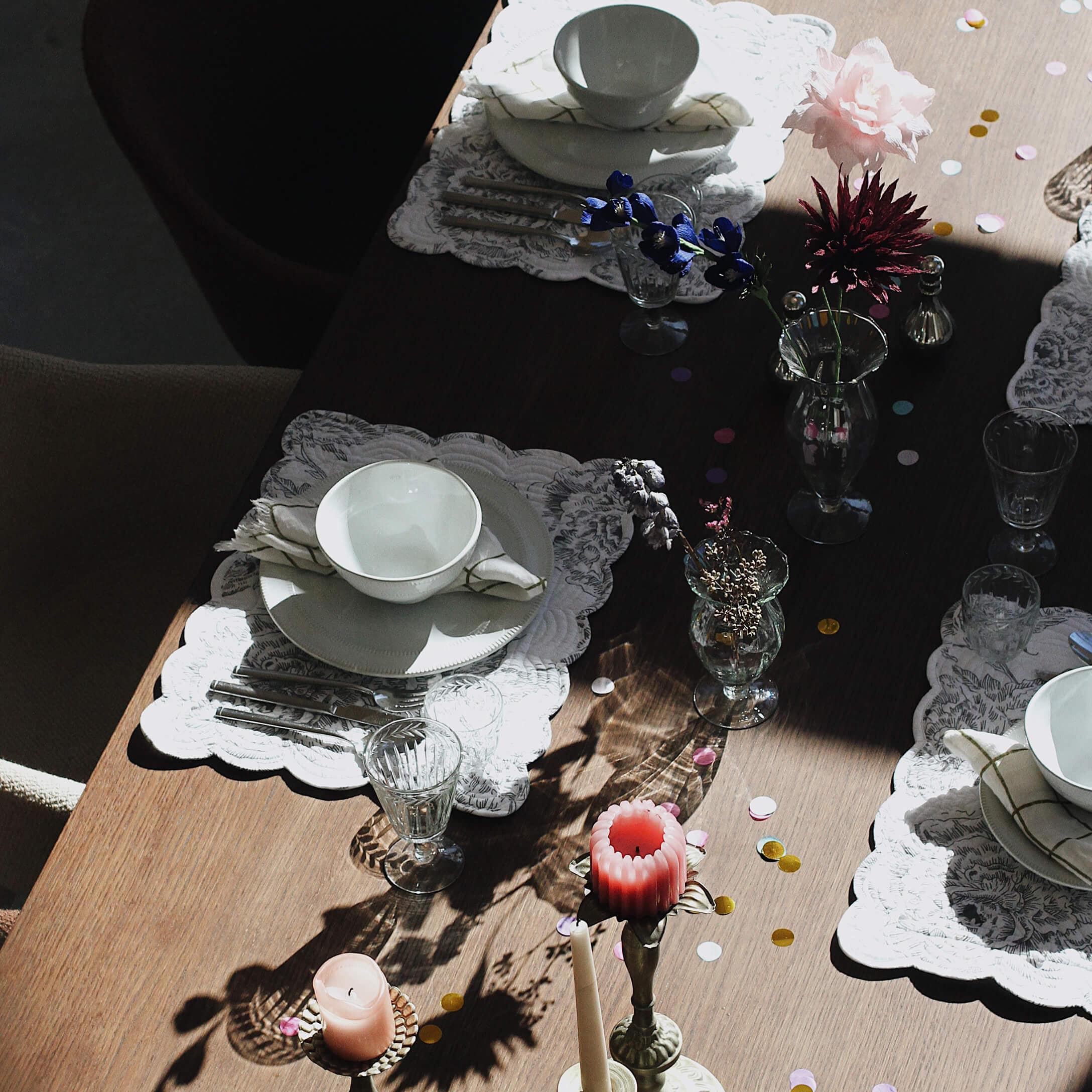 Table élégamment dressée avec vaisselle blanche, verres et bougies sur plateau en bois