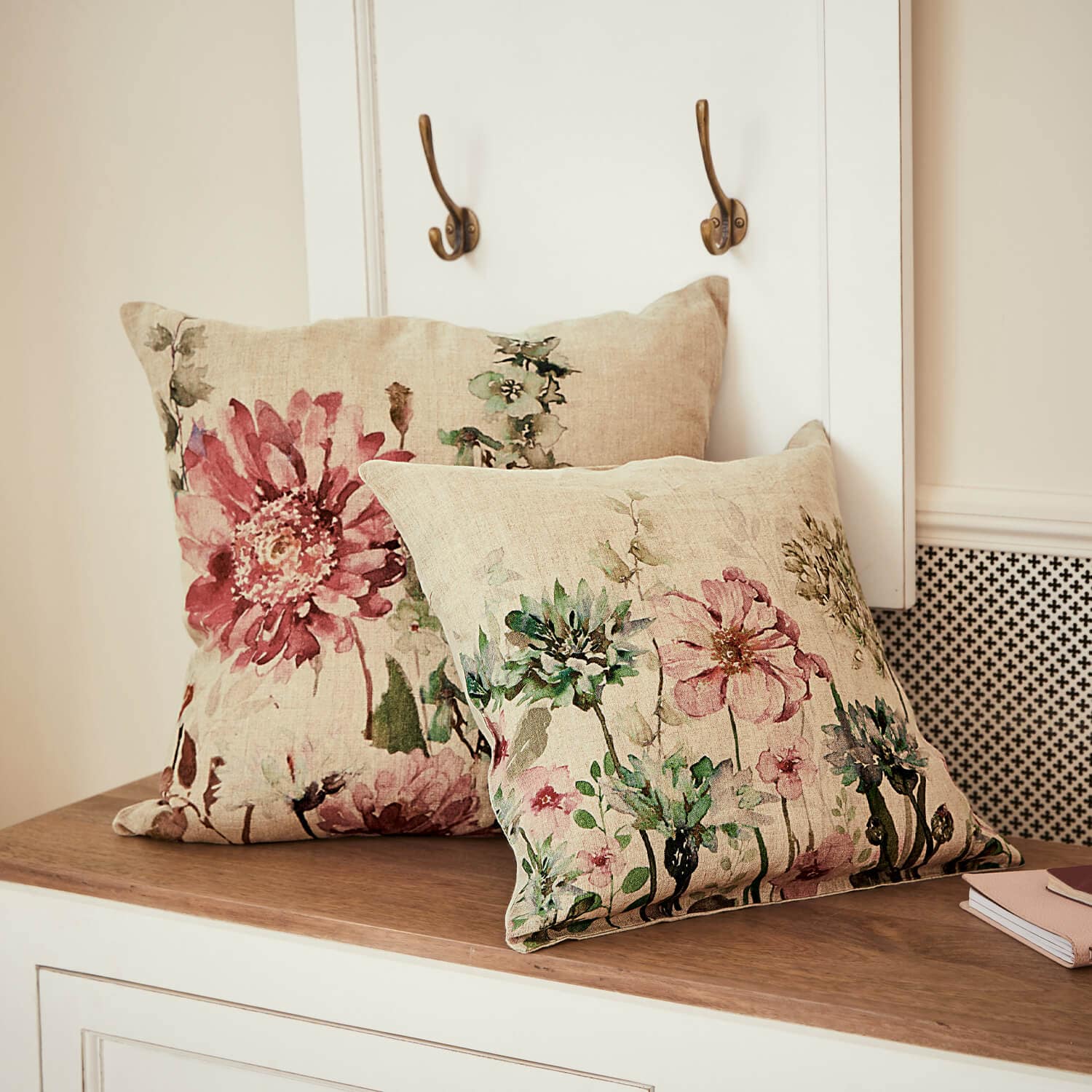 Deux coussins en lin avec imprimé floral pastel posés sur une surface en bois clair pour décoration intérieure