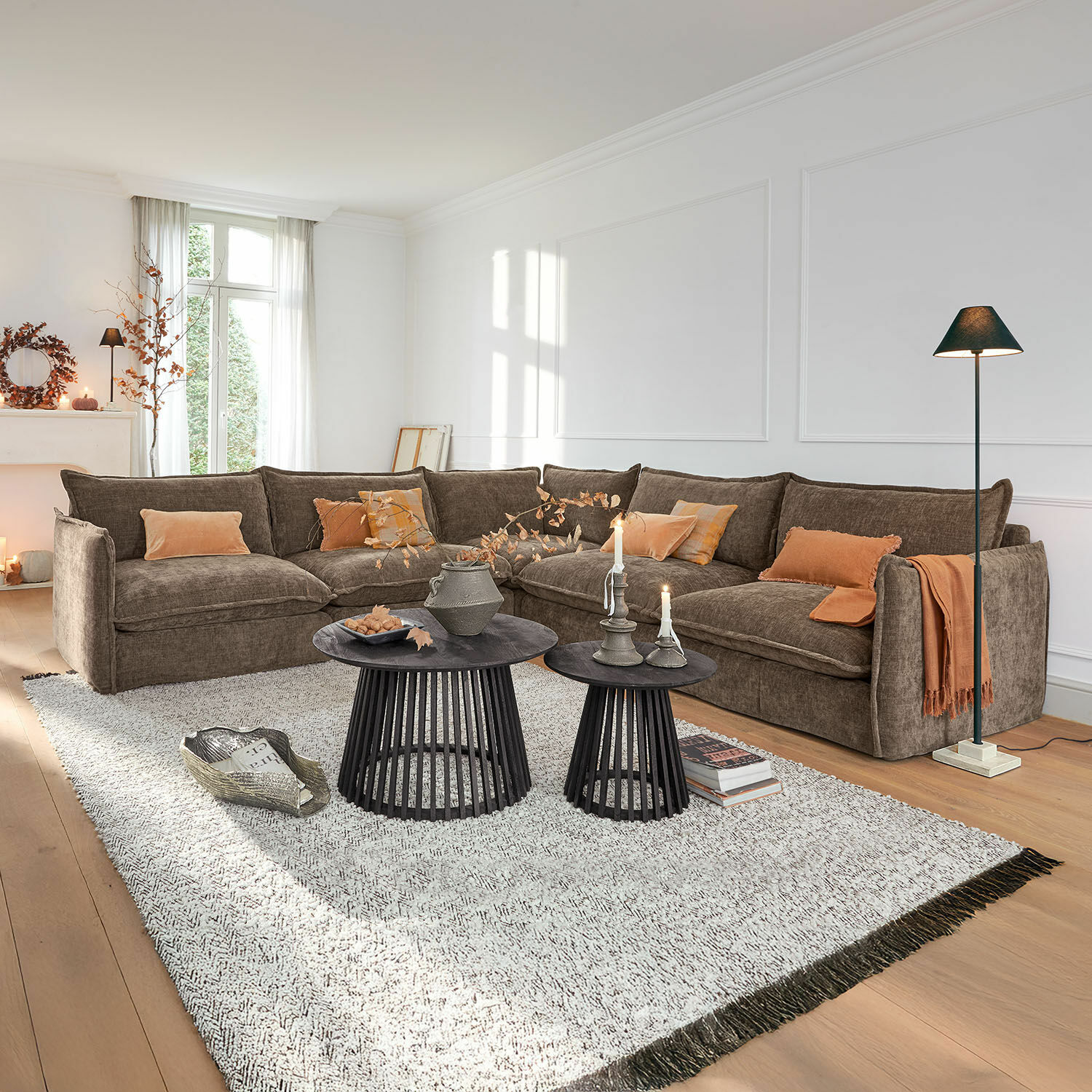 Canapé Illingworth Canapé d'angle en tissu marron avec coussins orange et tables basses noires dans un salon lumineux