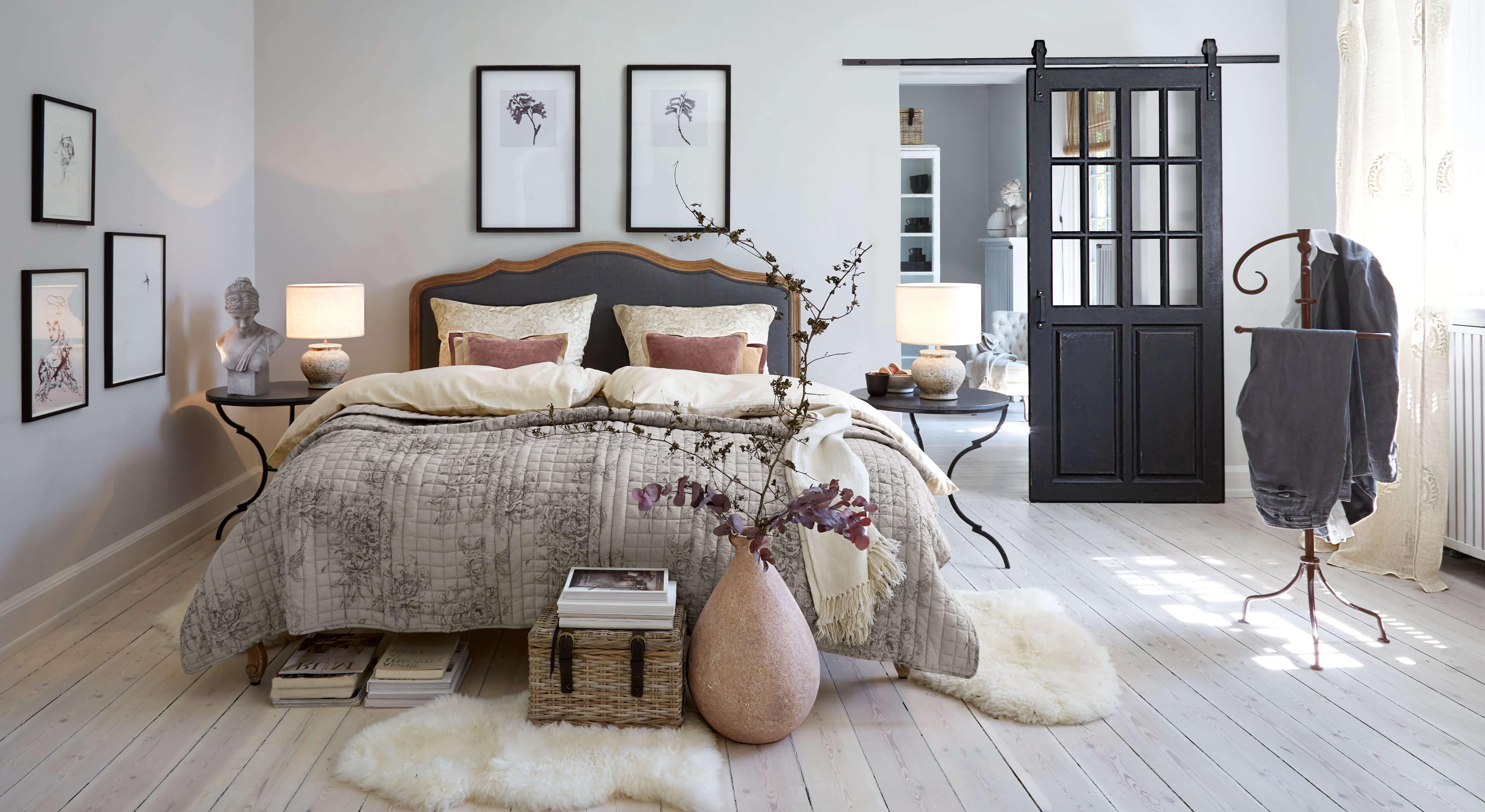 Chambre chaleureuse avec lit en linge gris-beige et tables de chevet noires avec lampes