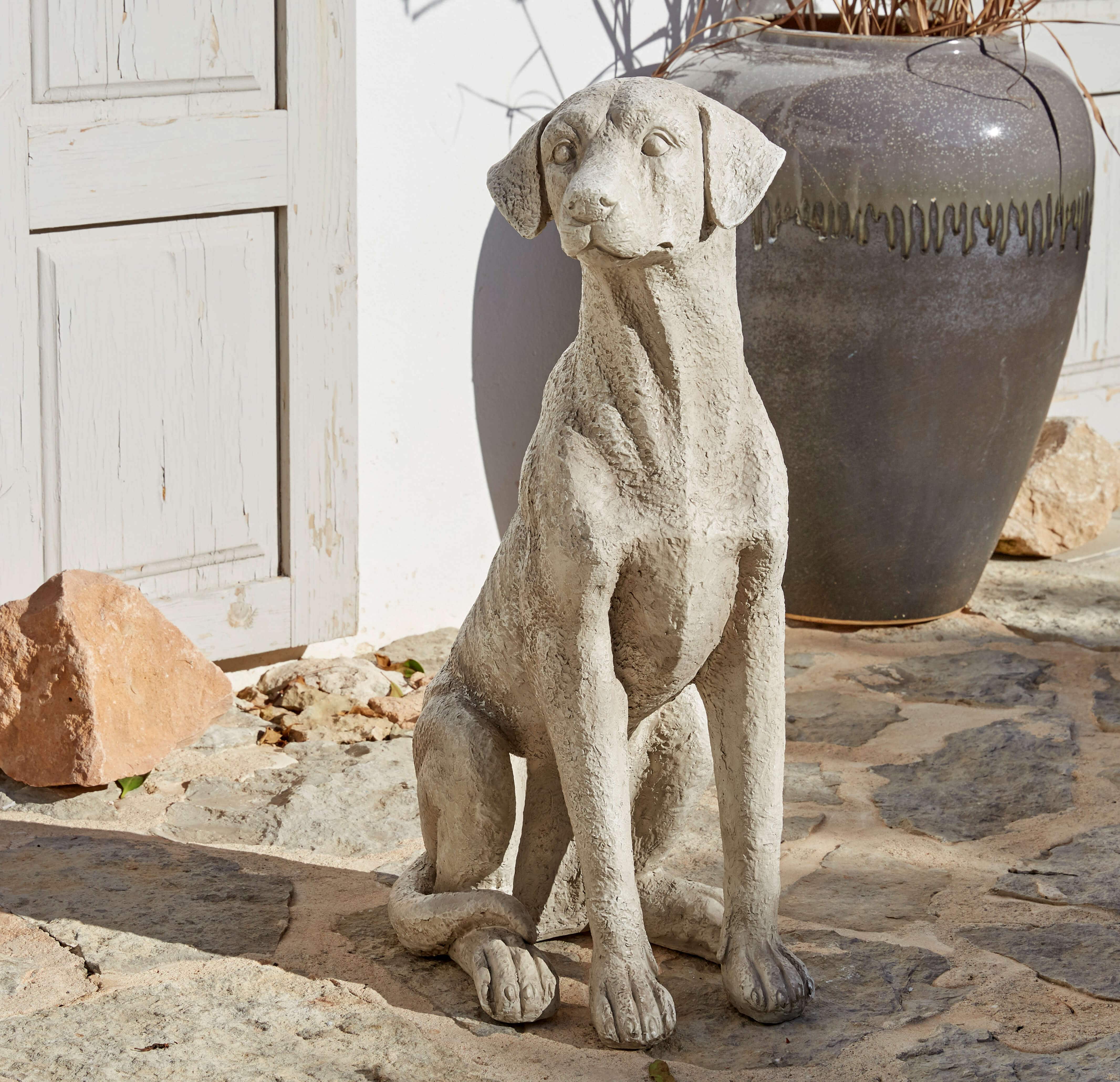 Statue de chien en béton gris posée sur sol en pierre, décoration extérieure élégante