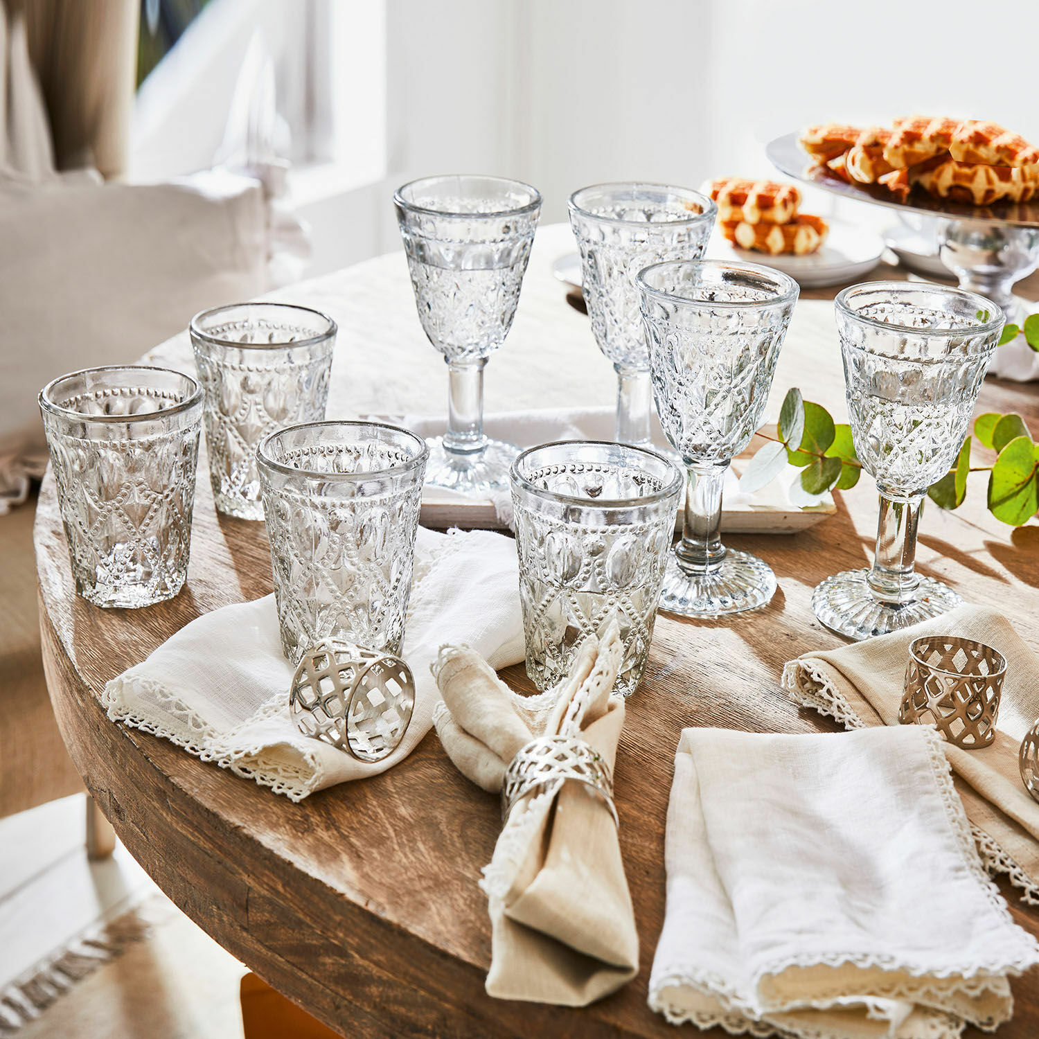 Lot de 8 verres Vérane Ensemble de verres et coupes en verre transparent à motif décoratif sur table en bois avec serviettes