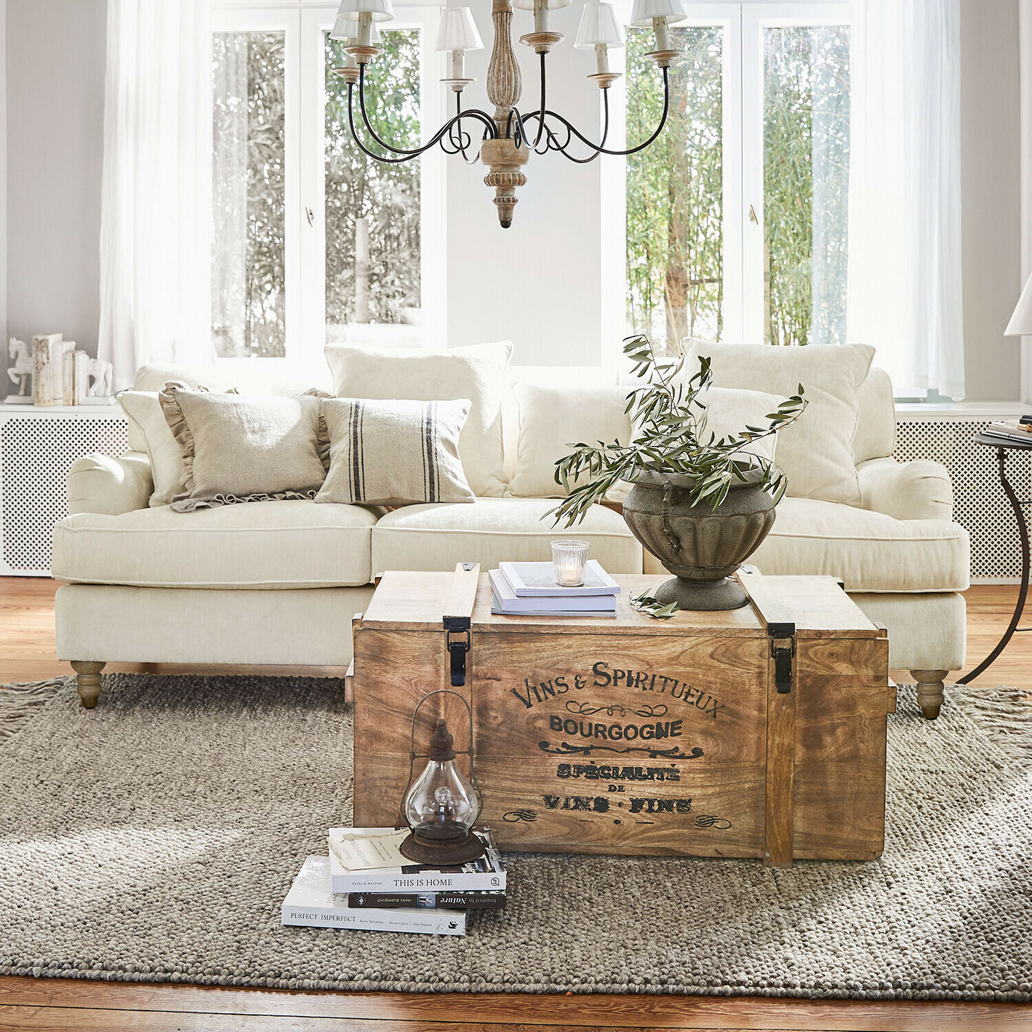 Canapé Isa Coffre en bois vintage utilisé comme table basse dans un salon clair avec canapé beige et décoration
