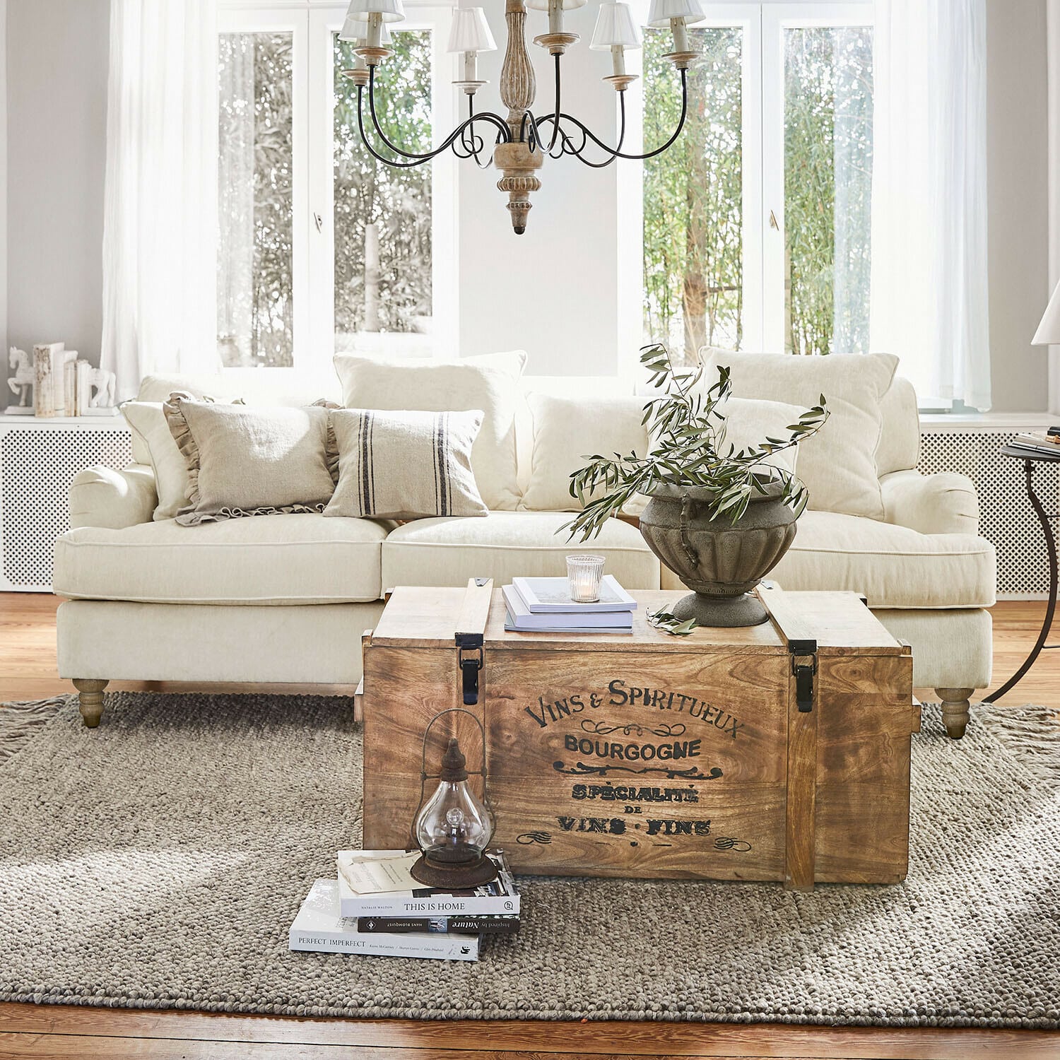 Canapé Isa Coffre en bois vintage utilisé comme table basse dans un salon clair avec canapé beige et décoration