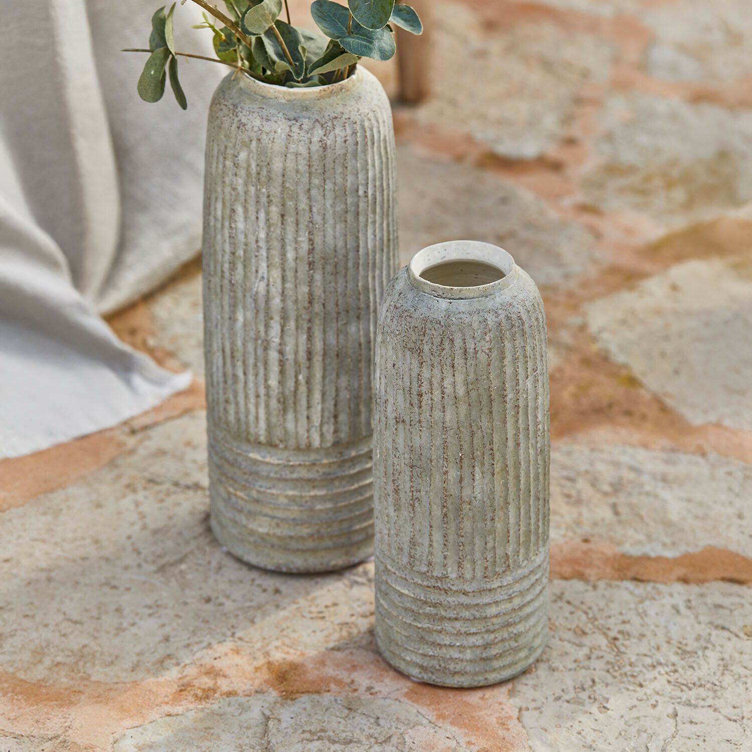 Lot de 2 vases Bellonas Deux vases en céramique grise avec rainures verticales posés sur un sol en pierre, décoration intérieure