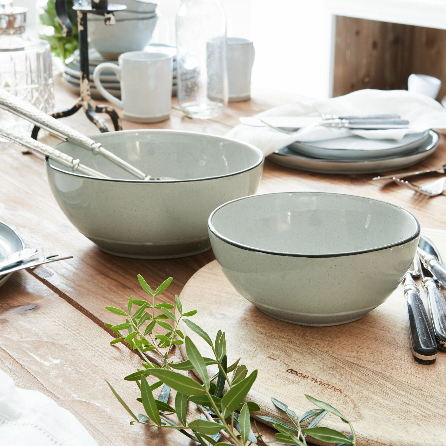 Lot de 2 saladiers Biarré Ensemble de bols en céramique gris clair sur une table en bois avec décoration de feuilles vertes