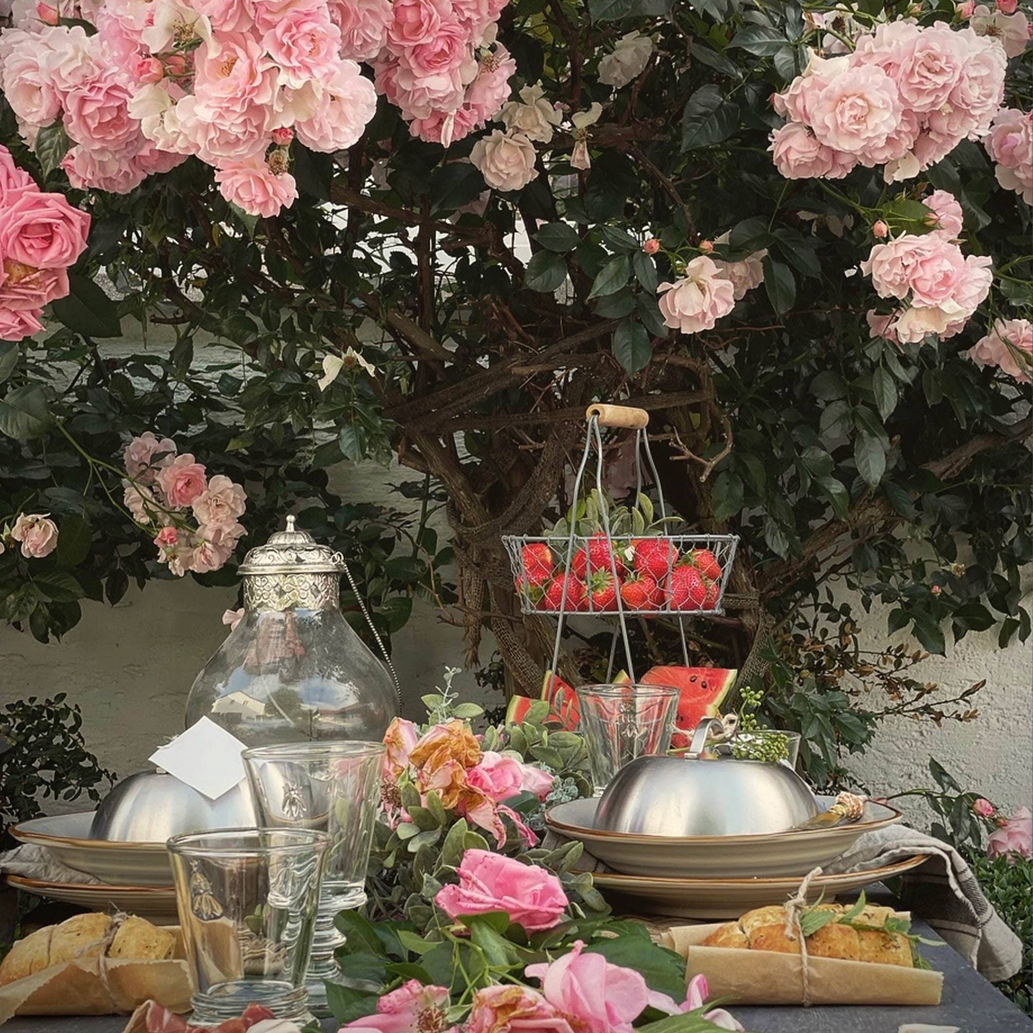 Table de jardin décorée de roses et fruits frais, parfaite pour un repas d'été en plein air