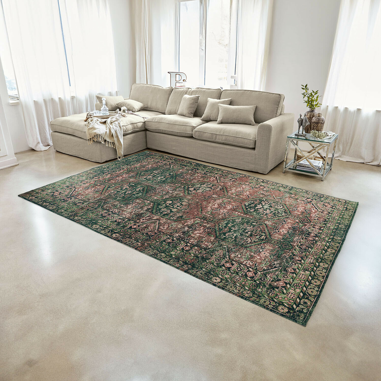 Tapis Incantaro Tapis à motif oriental vert et rose dans un salon lumineux avec canapé beige et table d'appoint en verre