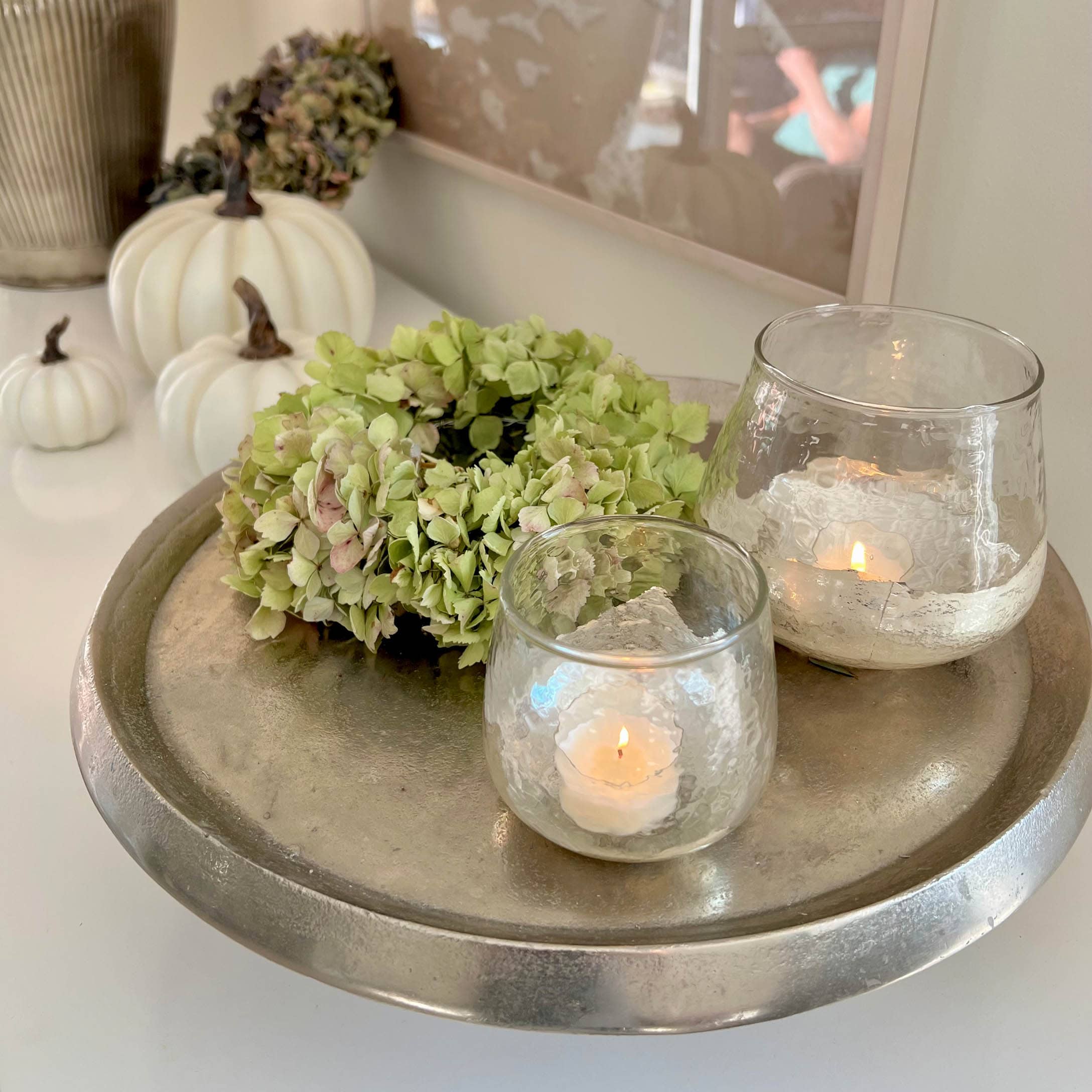 Plateau argenté décoratif avec couronne verte et deux photophores en verre avec bougies blanches