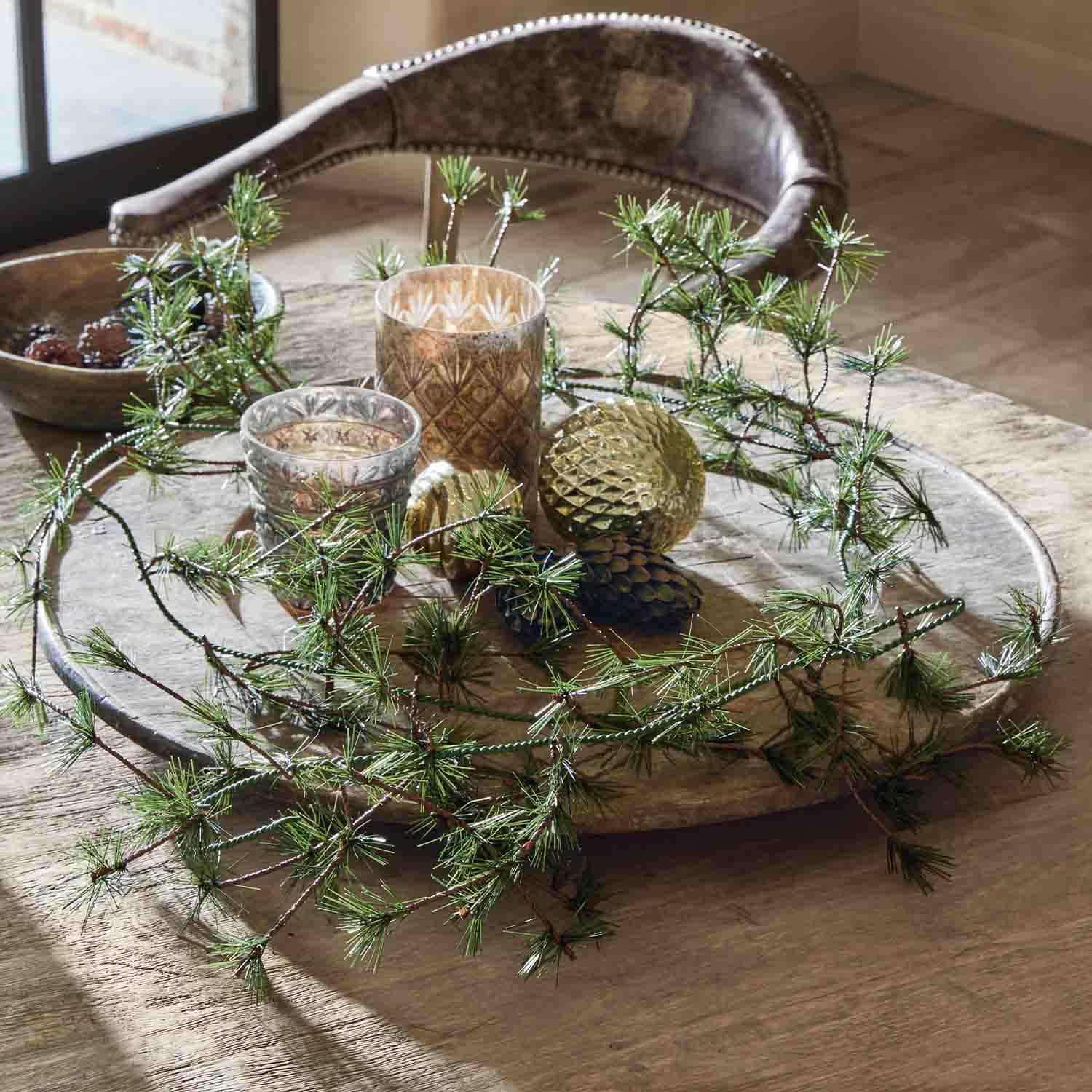 Plateau en bois décoré de branches vertes, boules dorées et photophores en verre sur une table