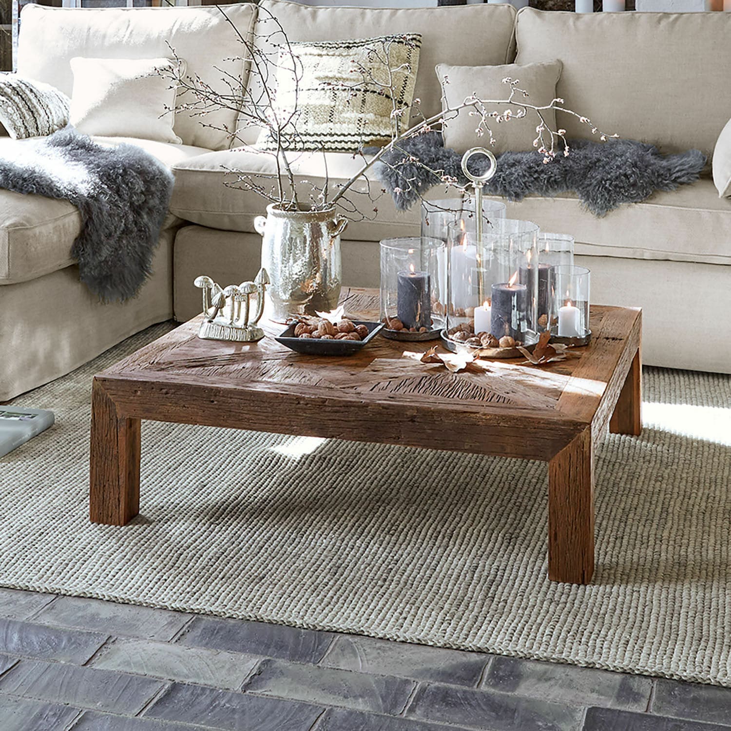 Table basse Vivacetto Table basse carrée en bois avec bougies décoratives et éléments naturels sur tapis beige dans un salon