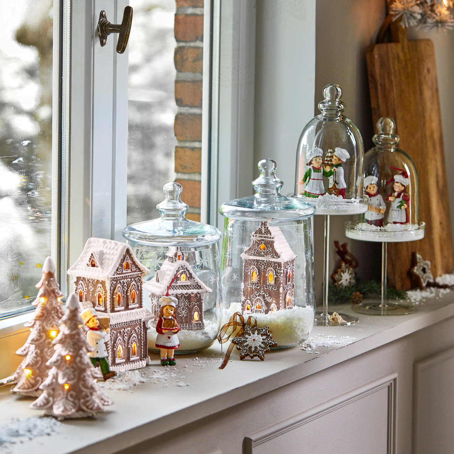 Décorations de Noël avec maisons en pain d'épices et figurines sous cloches en verre sur le rebord de fenêtre