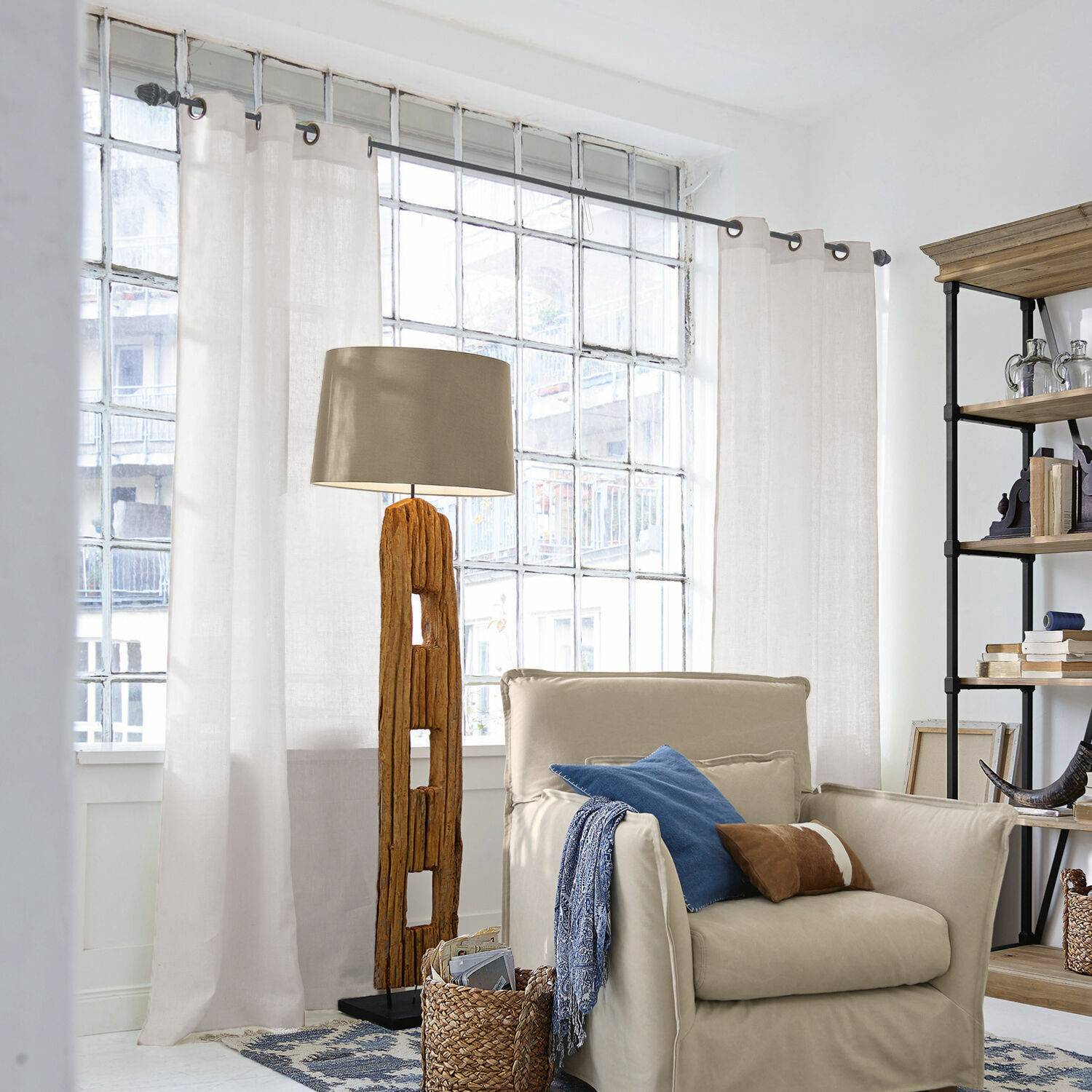 Rideau Salinas Lampadaire en bois avec abat-jour beige dans un salon lumineux avec fauteuil et étagère