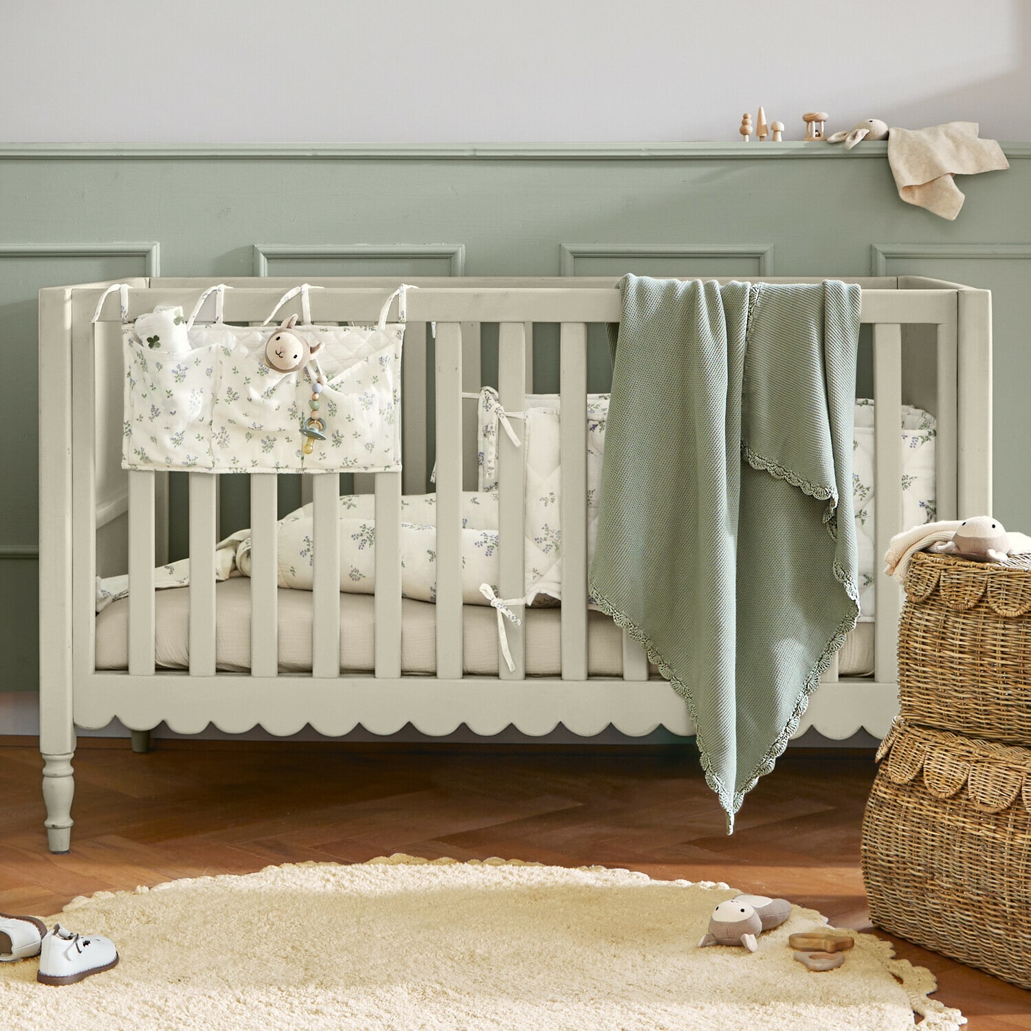 Lit bébé Leily Lit bébé en bois beige avec couverture verte et literie à motif floral dans une chambre d'enfant chaleureuse