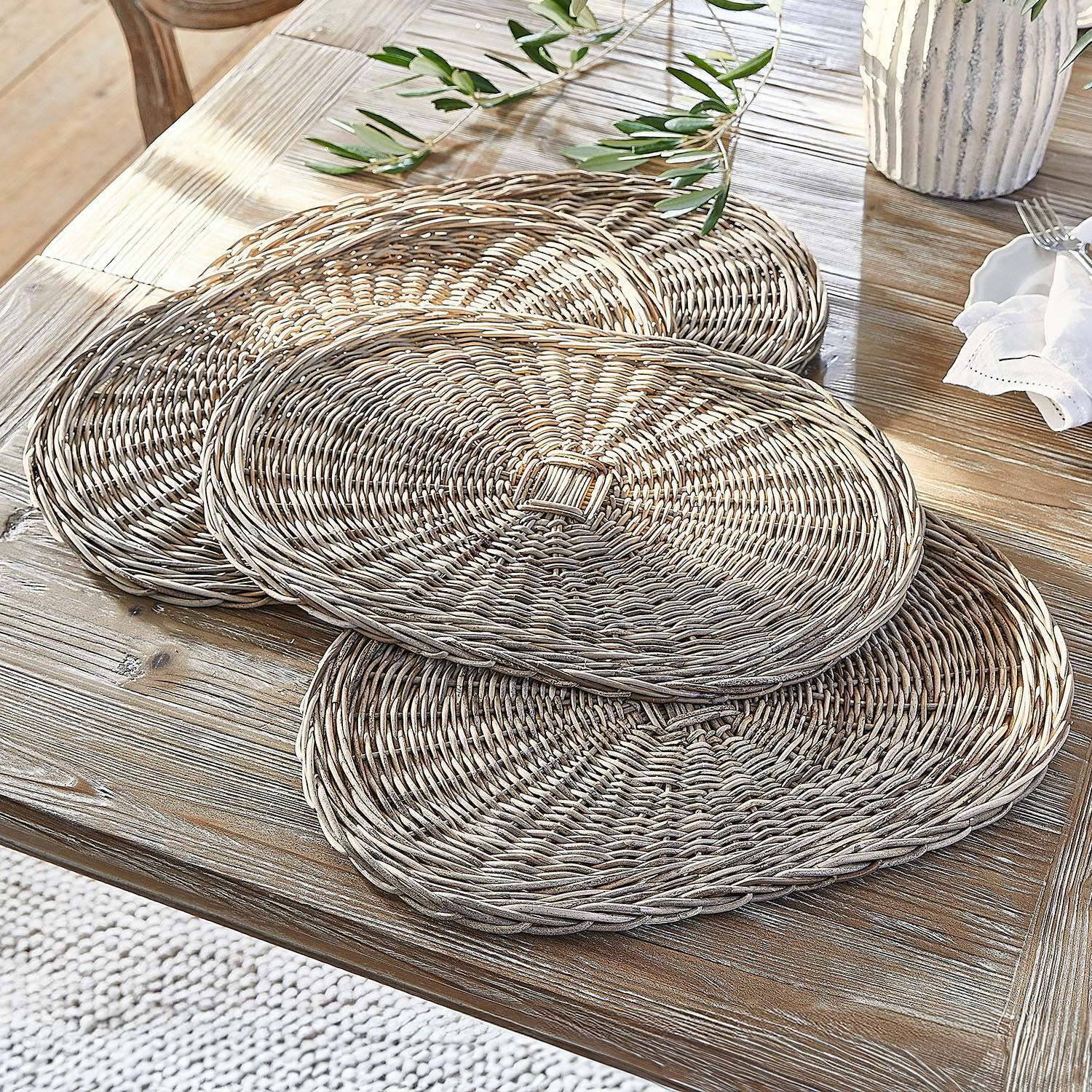 Lot de 4 sets de table Villoray Ensemble de sets de table ronds en osier naturel posés sur une table en bois clair