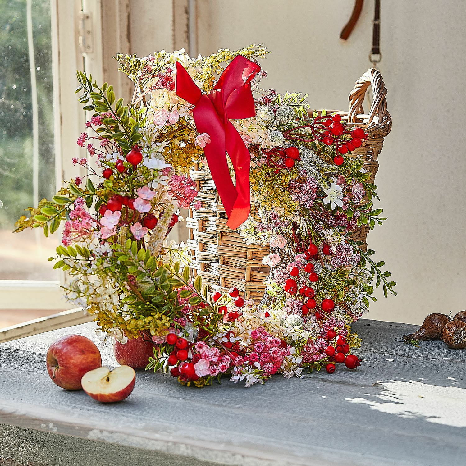 Couronne Selivane Couronne décorative avec baies rouges et fleurs roses sur panier en osier posé sur une table
