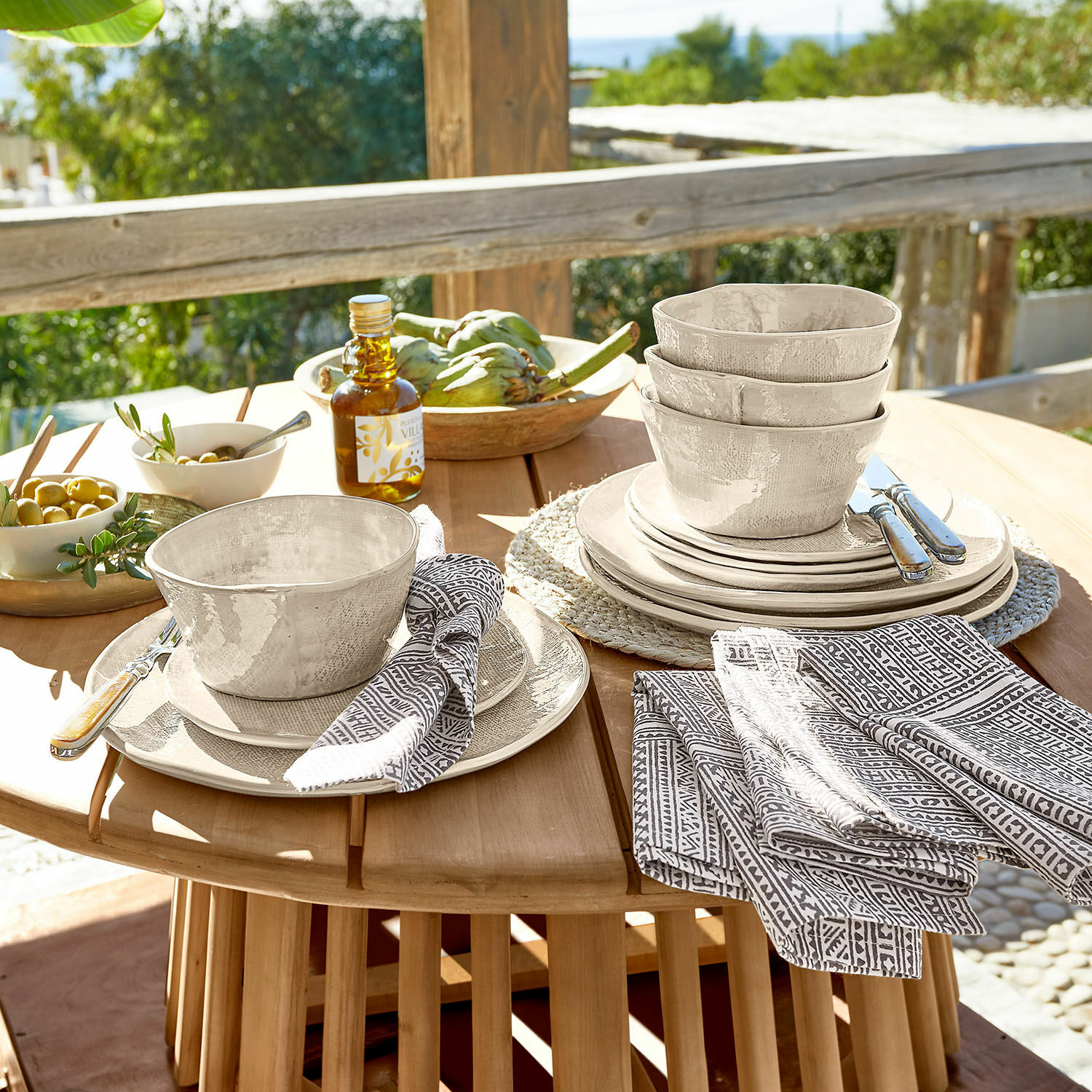 Service 12 pièces Luganville Ensemble de vaisselle en céramique beige avec bols et assiettes sur table en bois en extérieur