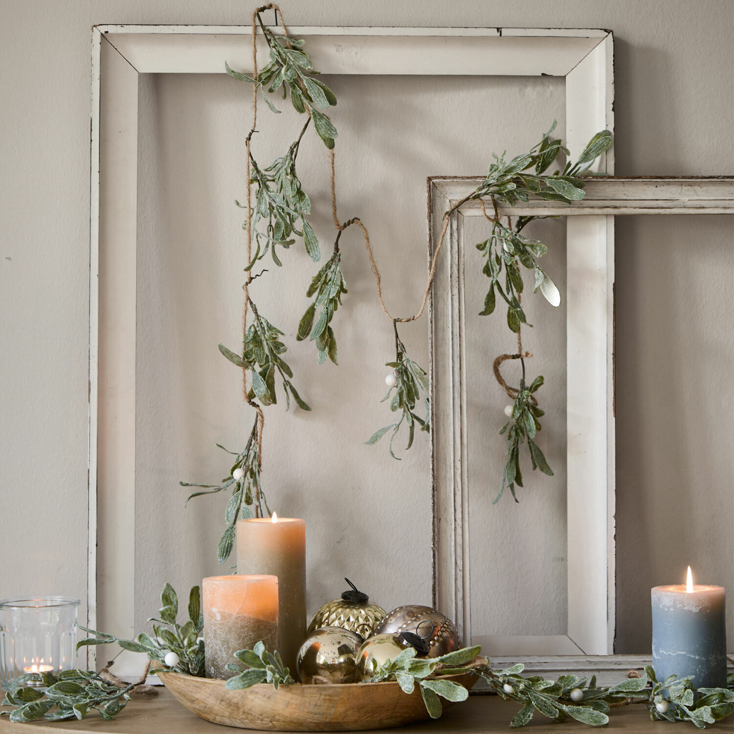 Guirlande Mistletoe Guirlande décorative avec feuilles vertes et baies blanches sur cadres en bois blanc, bougies et décorations
