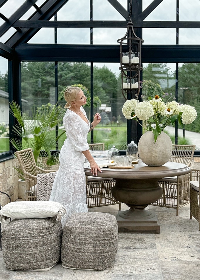 Intérieur chaleureux d'une véranda avec table ronde en pierre et chaises en osier, décoration florale