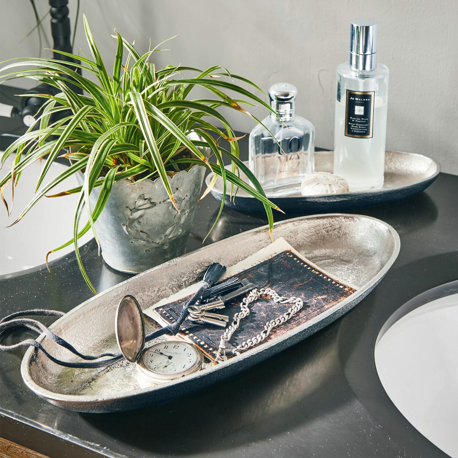 Lot de 2 coupes Marné Plateau décoratif en métal argenté avec clés et montre sur un comptoir de salle de bain noir