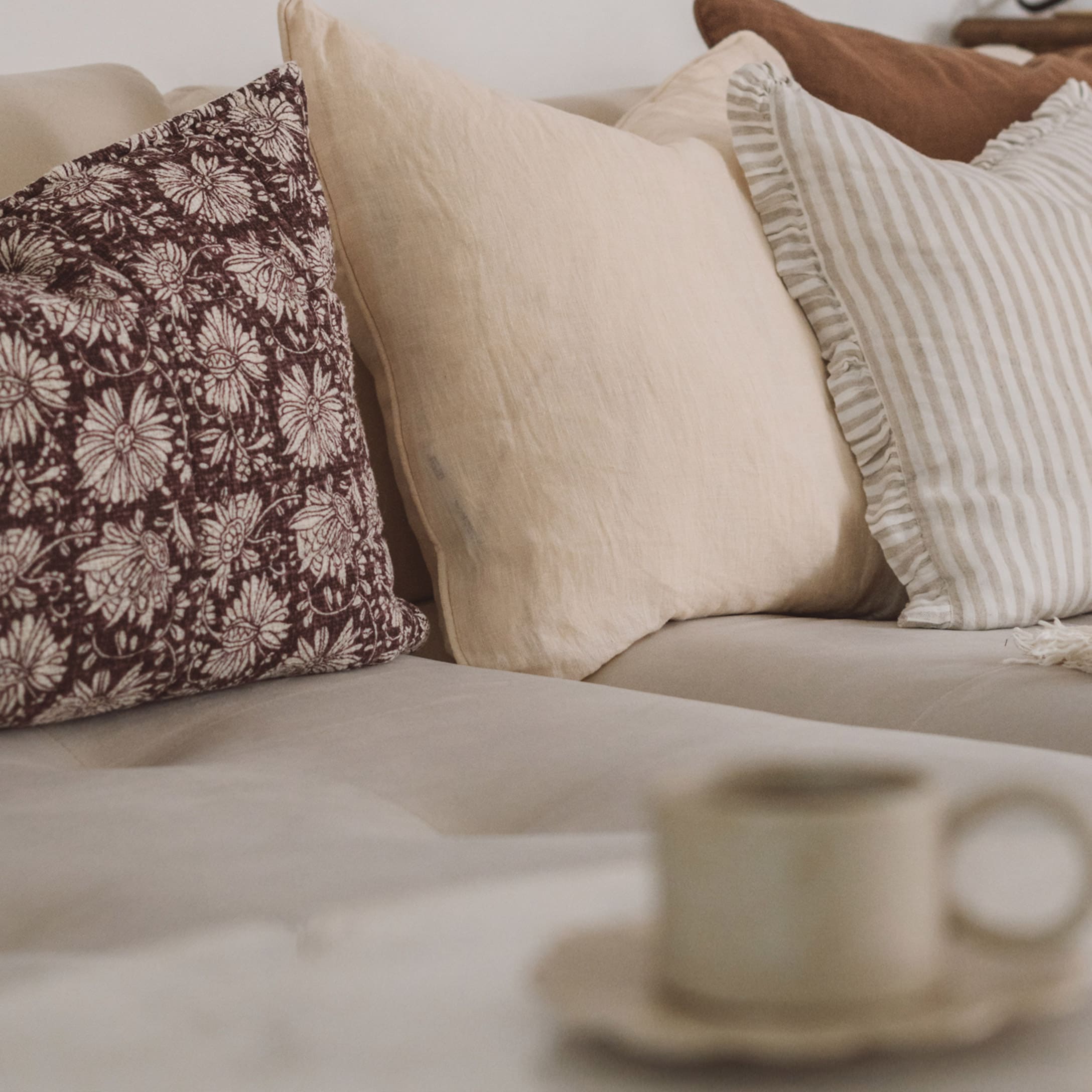 Ensemble de coussins décoratifs beige et marron sur un canapé clair dans un salon cosy