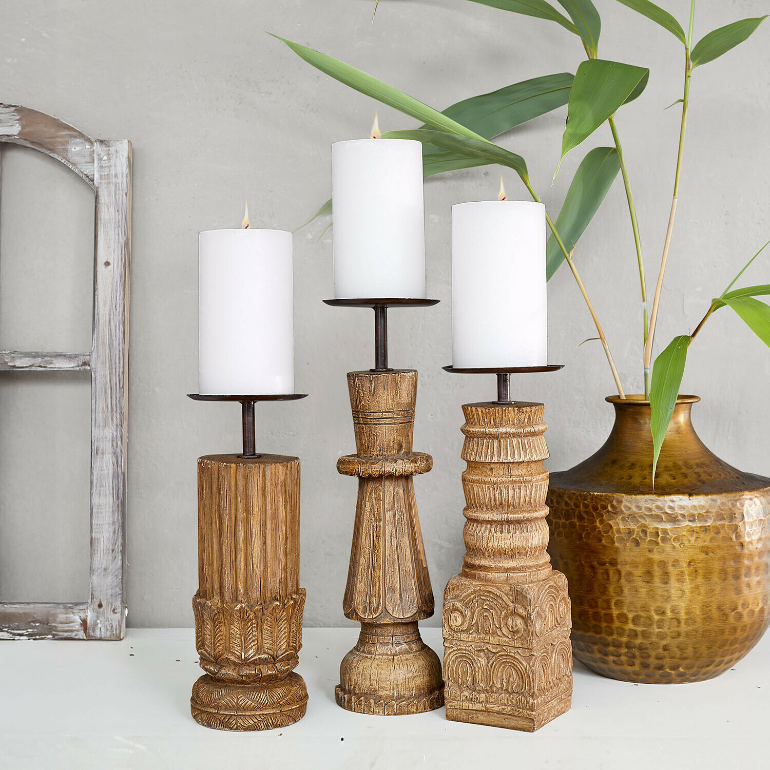 Lot de 3 bougeoirs Zahirah Ensemble de trois bougeoirs en bois sculpté avec bougies blanches, finition naturelle et motifs décoratifs