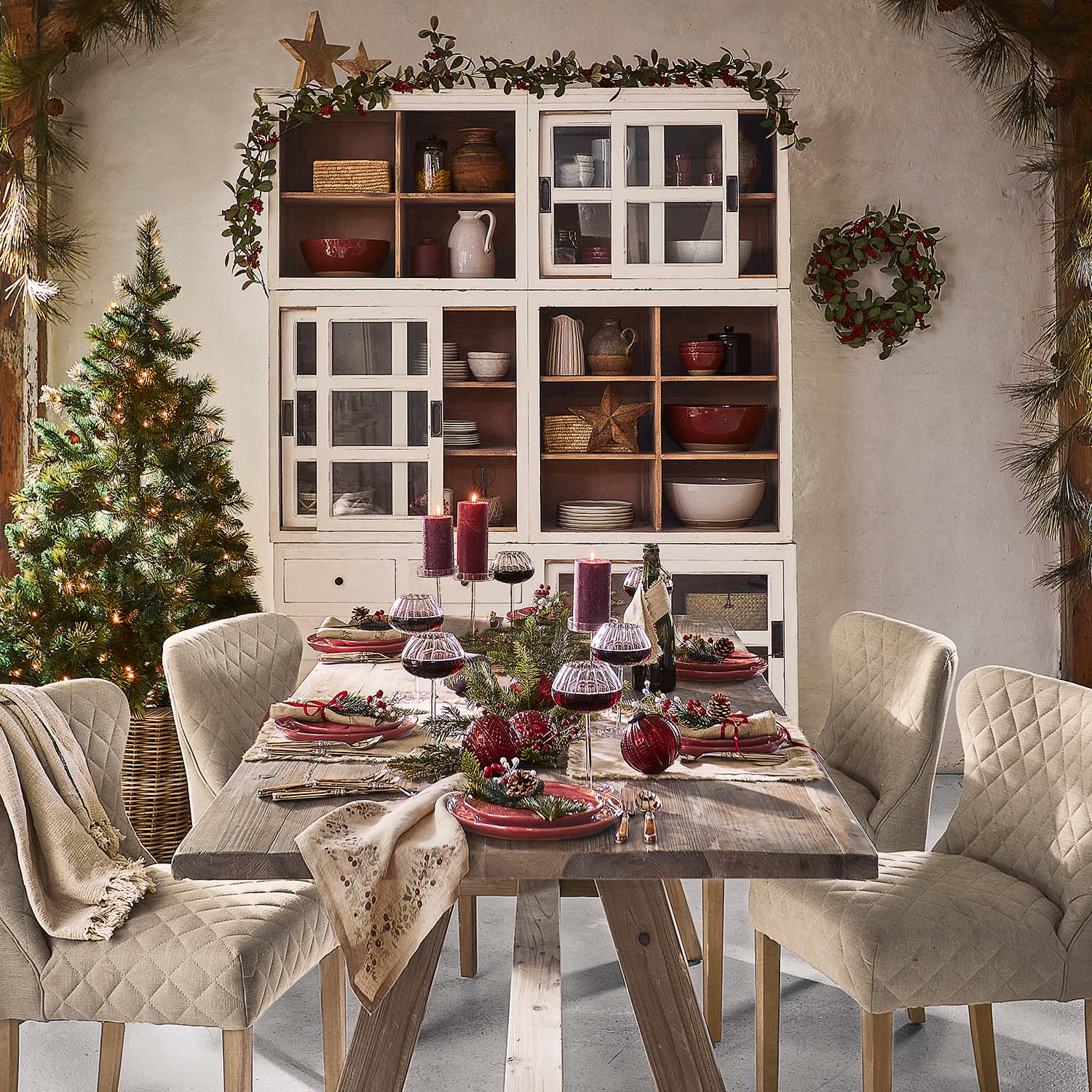 Table en bois rustique avec chaises beige matelassées et décoration de Noël dans une salle à manger