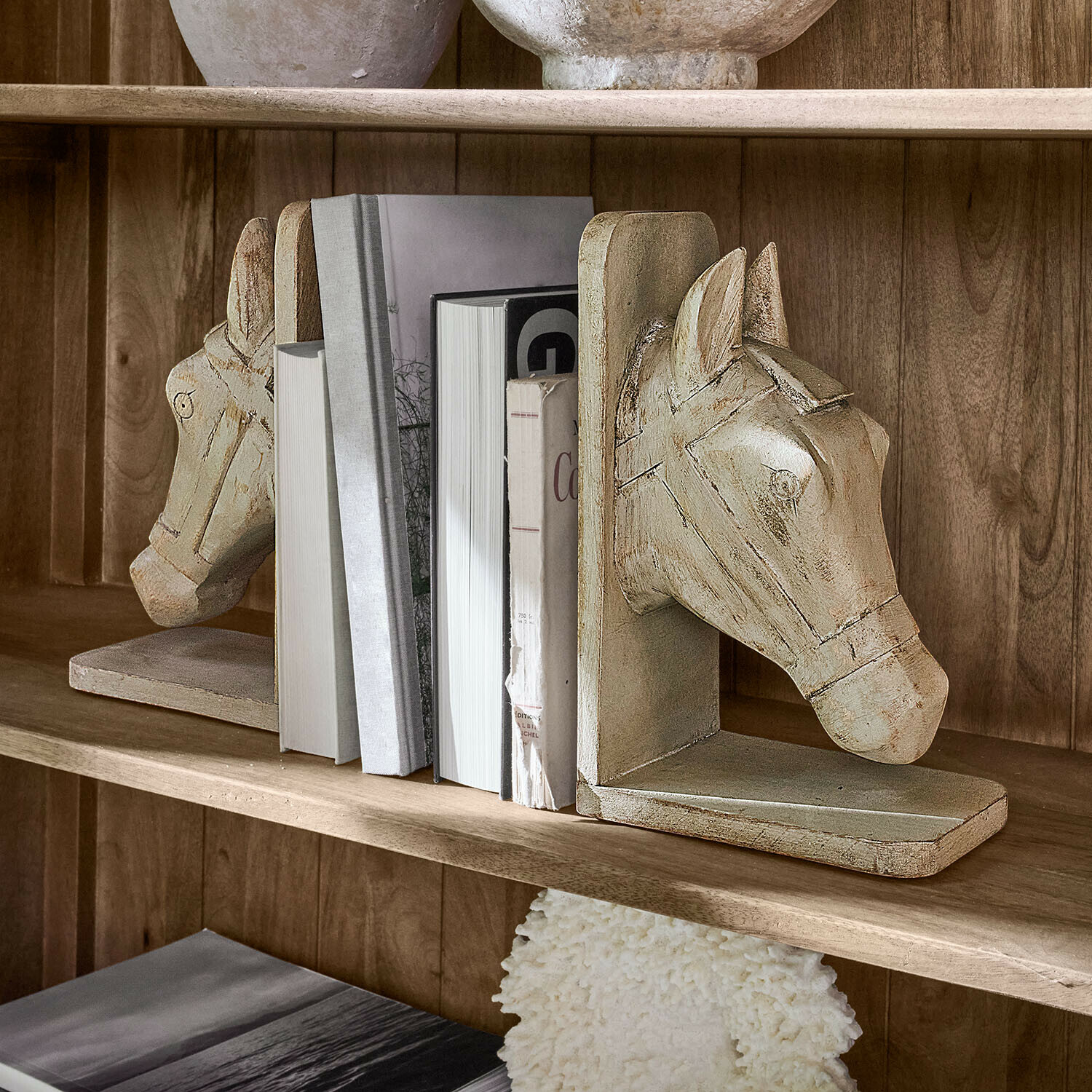 Lot de 2 serre-livres Caravena Paire de serre-livres en bois beige en forme de tête de cheval sur une étagère avec des livres