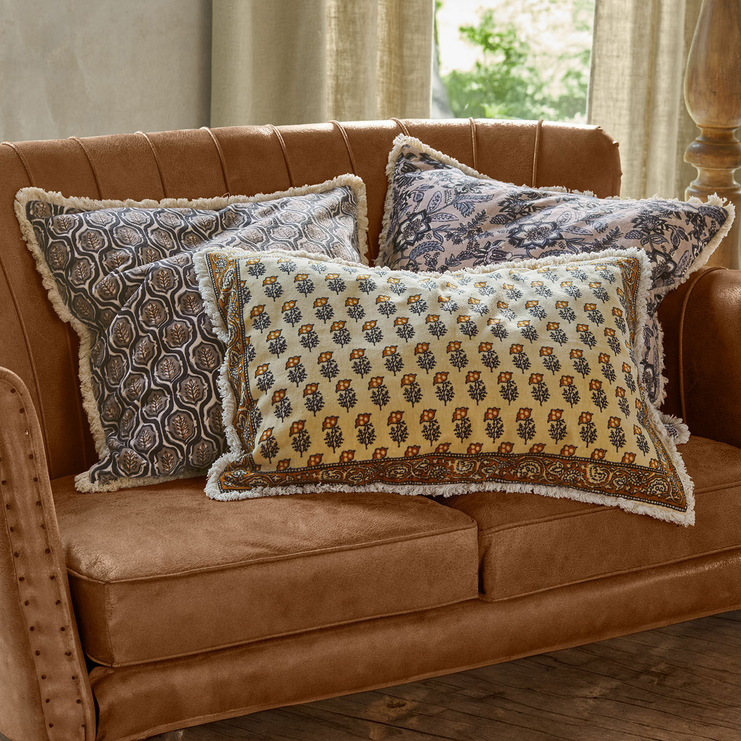 Lot de 3 housses de coussins Zandora Trois coussins décoratifs en coton à motifs floraux sur un canapé marron pour salon