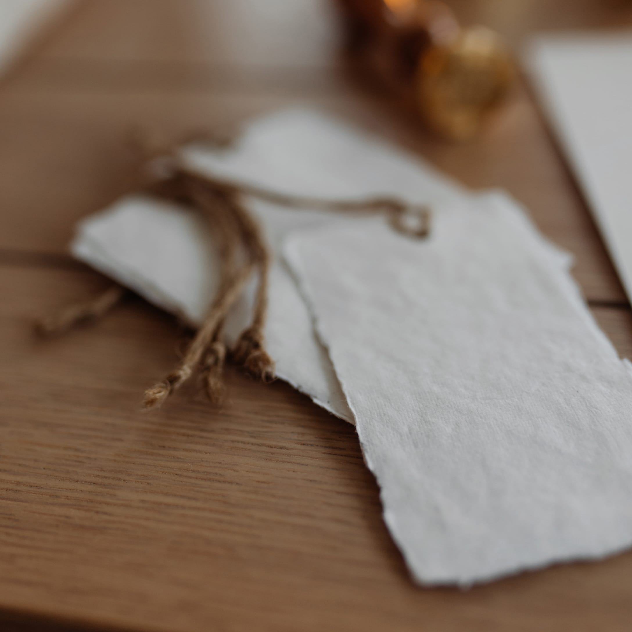 Étiquettes blanches en papier avec ficelle naturelle pour emballage cadeau sur table en bois